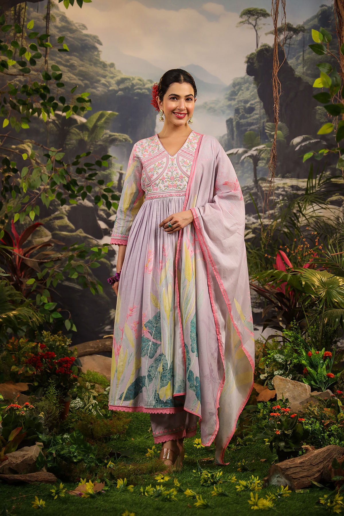 Woman in a traditional outfit standing in a lush green forest
