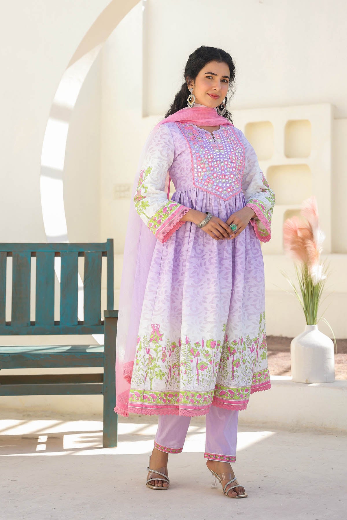 Woman wearing a light purple traditional outfit with pink accents in a bright room.