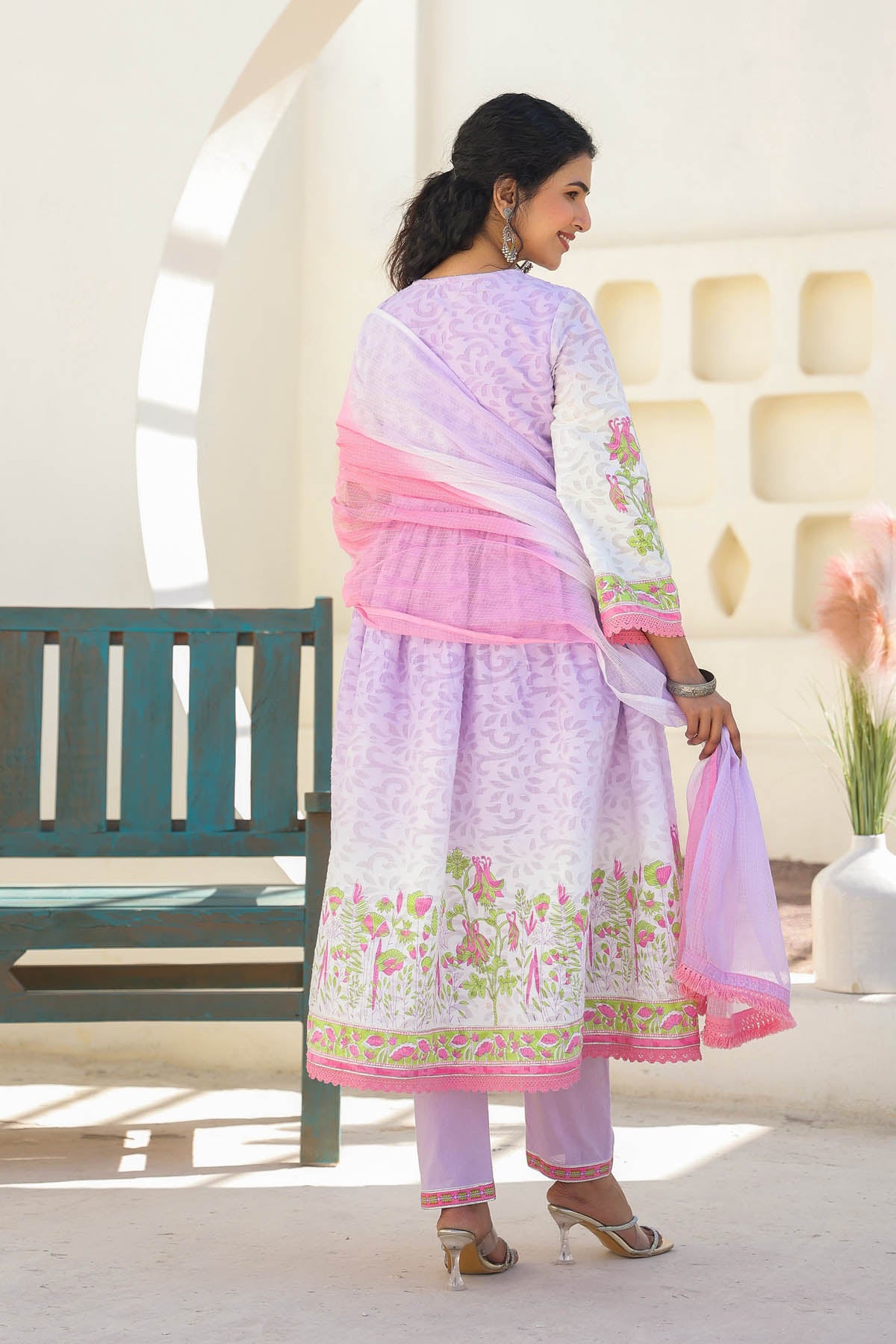 Woman in a light purple and pink traditional outfit standing in a bright room.
