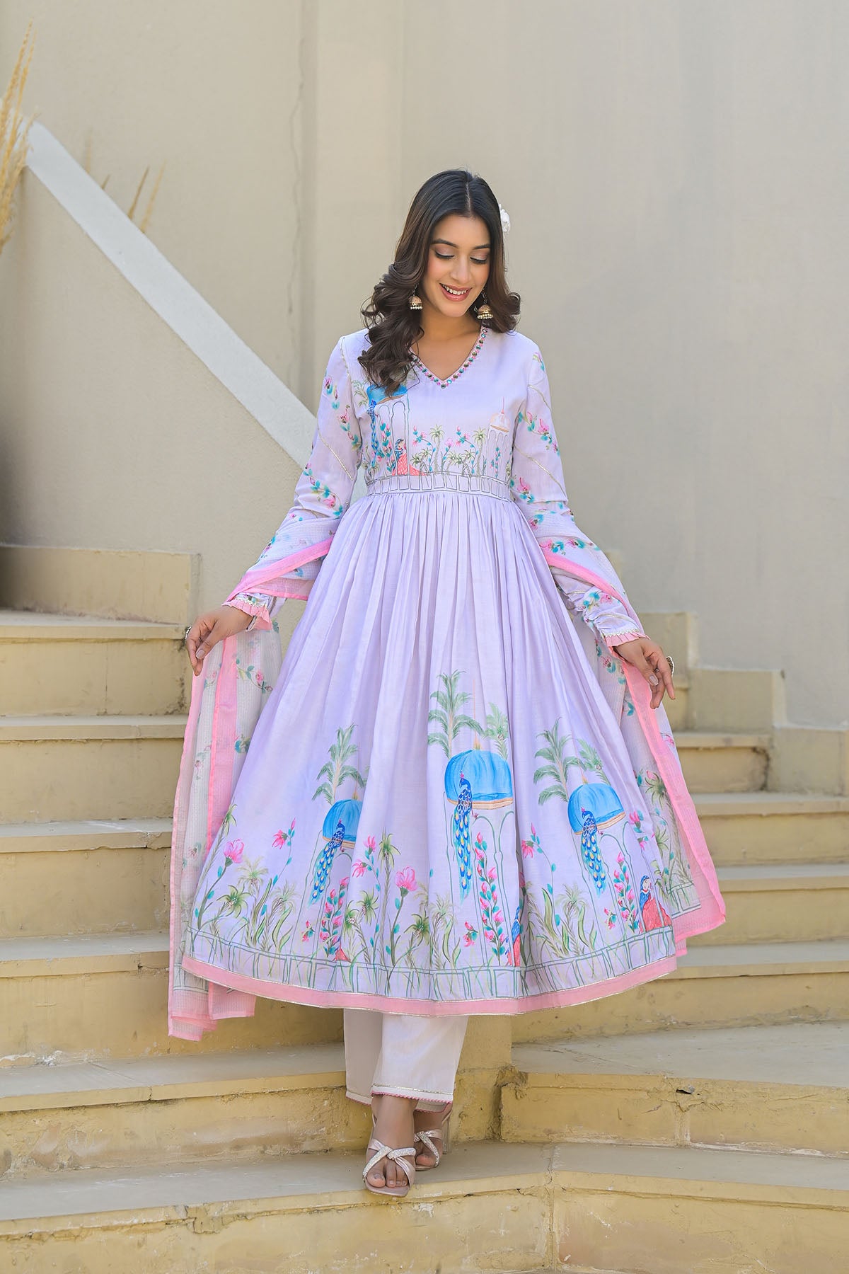 Woman in a light purple embroidered dress standing on steps with a neutral background