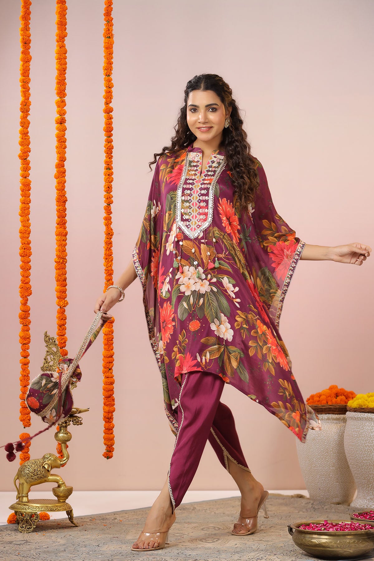 Woman in a colorful traditional outfit standing in front of decorative elements.