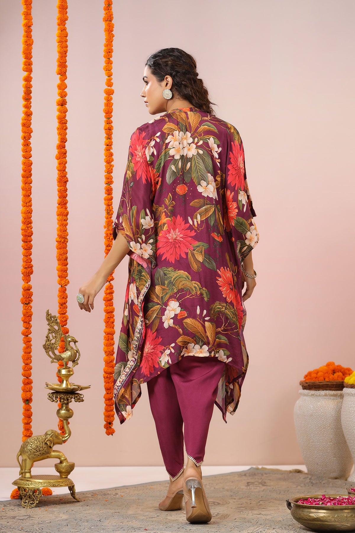 Woman in a floral outfit standing in a decorated indoor setting with marigold flowers and traditional decor.