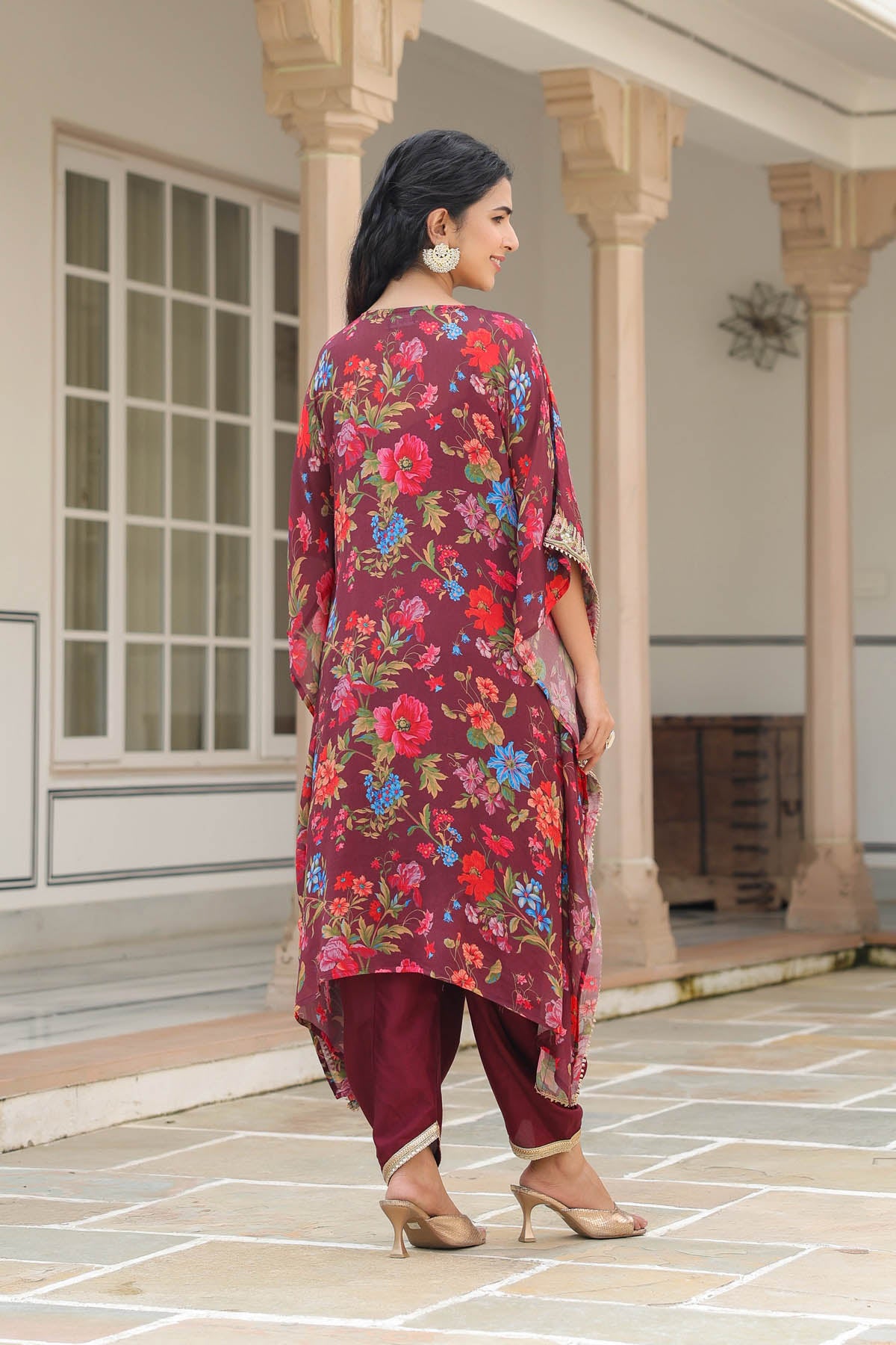 Woman wearing a floral kurta with red and purple pants in an outdoor setting.