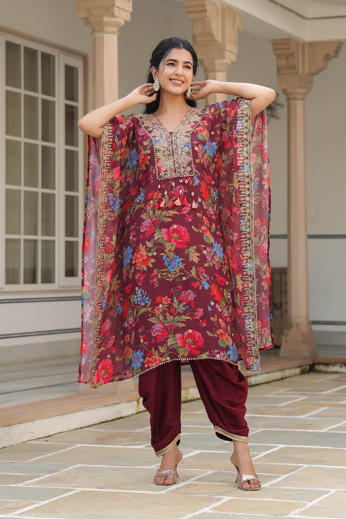 Woman wearing a colorful floral dress with a matching dupatta in an outdoor setting.