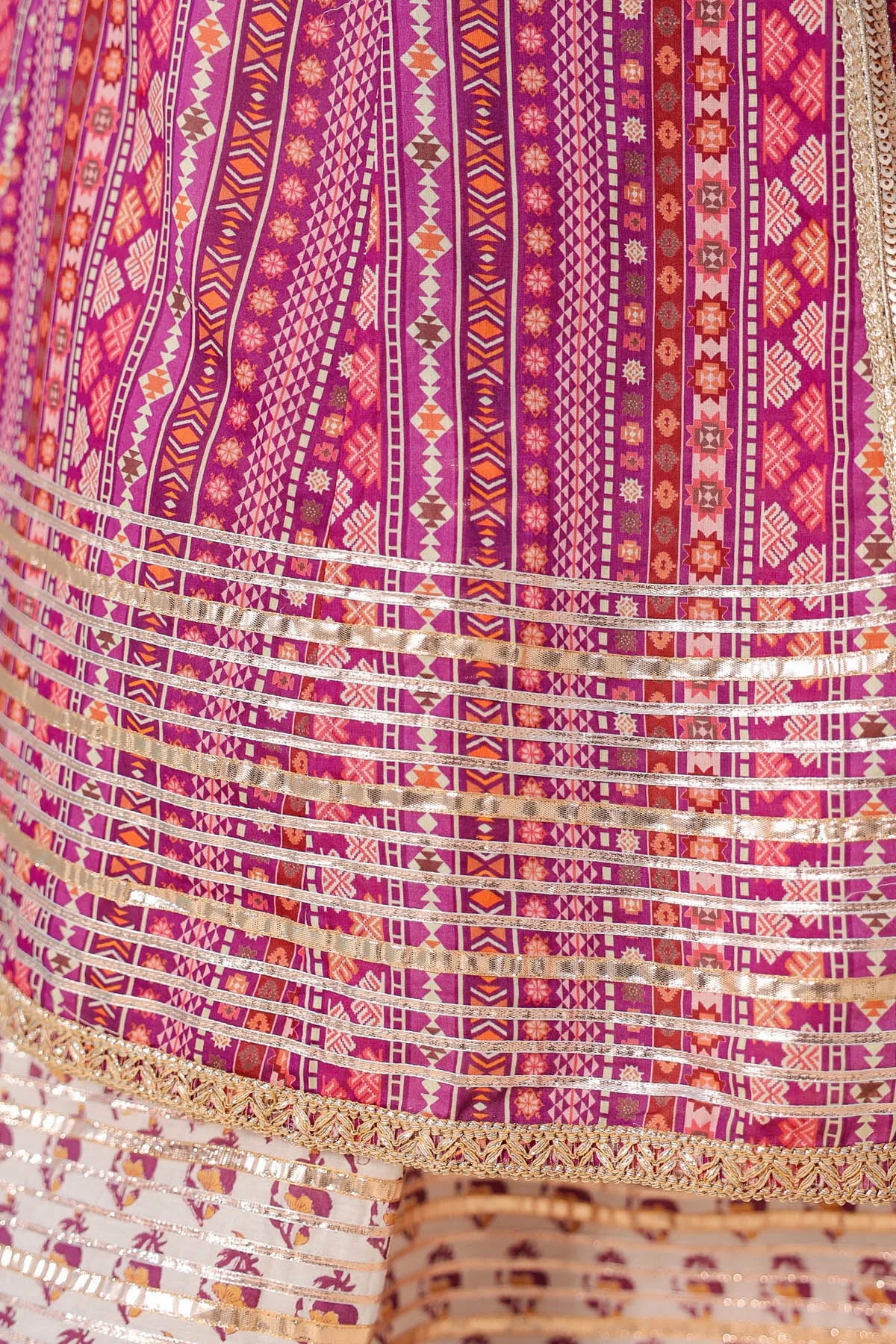 Close-up of a vibrant, patterned fabric with a mix of pink, purple, and gold colors.