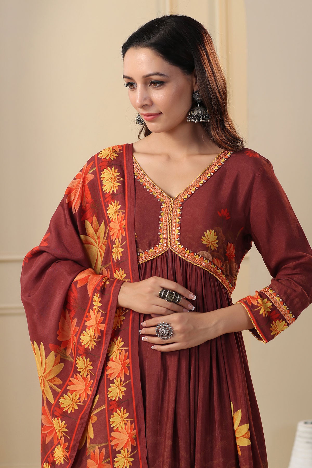 Woman wearing a maroon dress with floral patterns and embroidery.