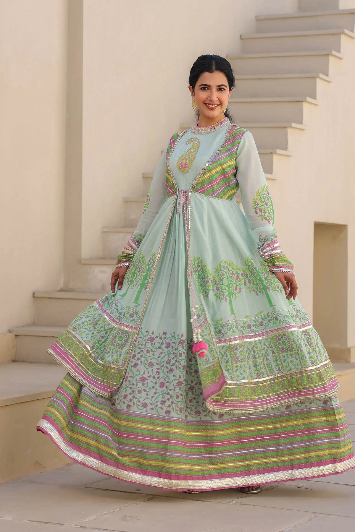 Woman in a traditional outfit standing on steps with a neutral background