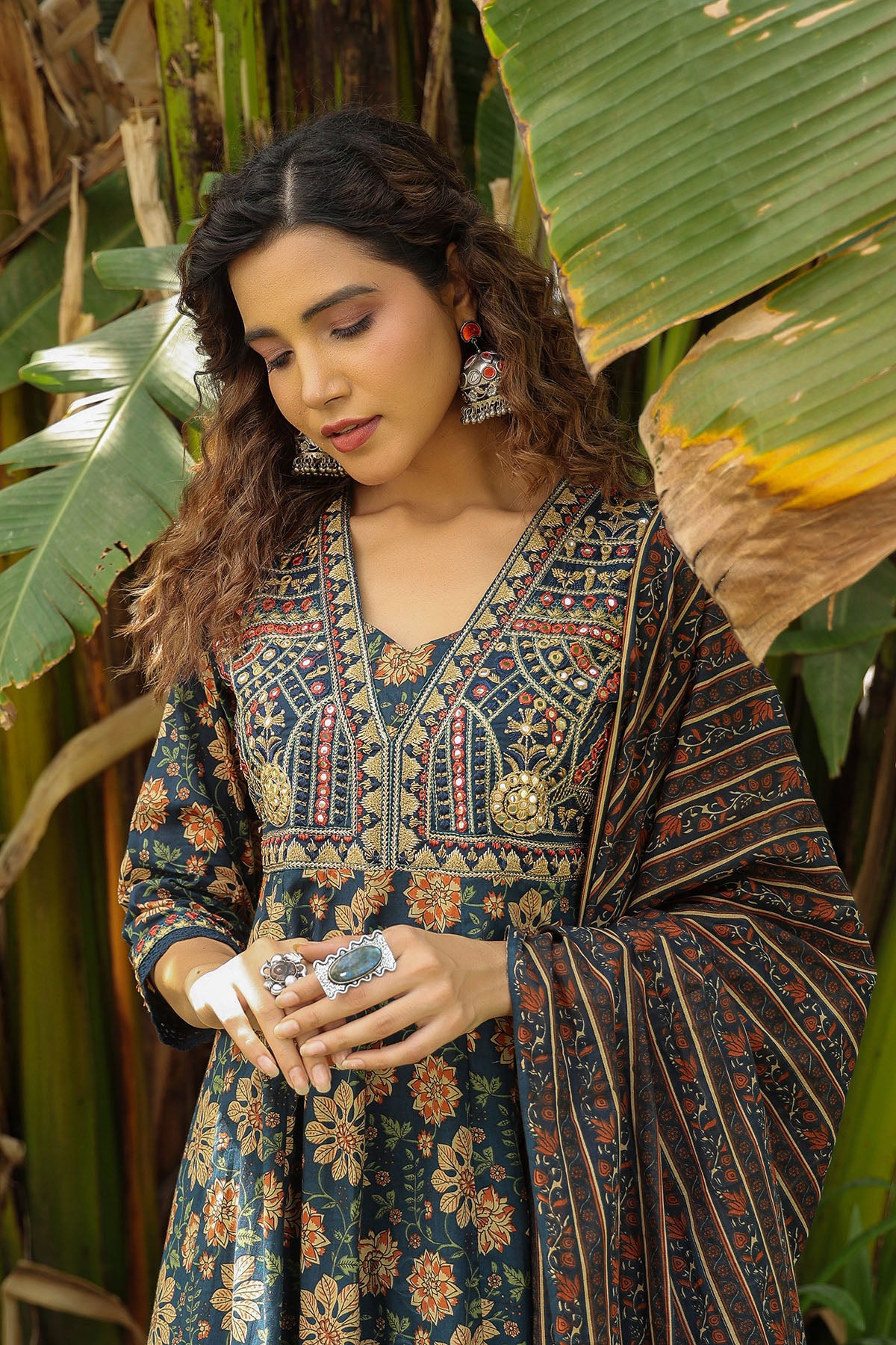 Woman in a patterned dress standing among large green leaves