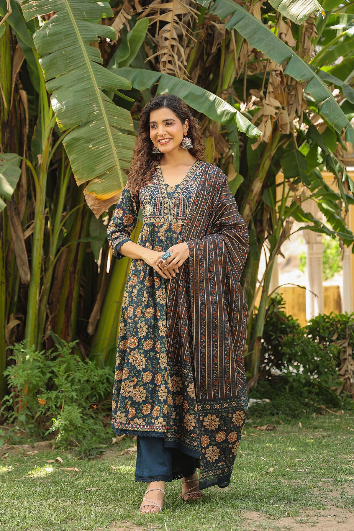 Woman in traditional outfit standing among banana trees