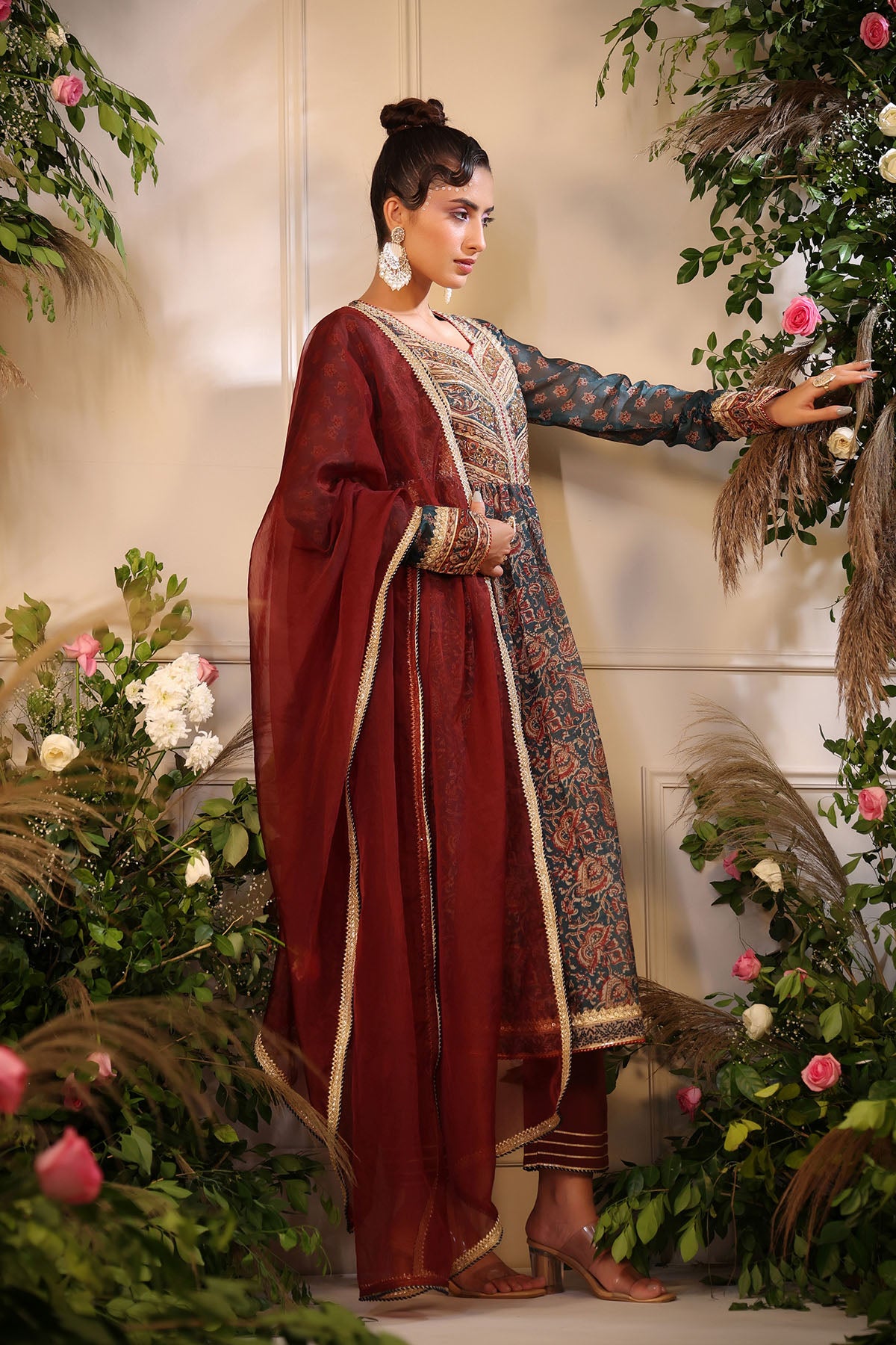 Woman in traditional attire standing among floral decorations