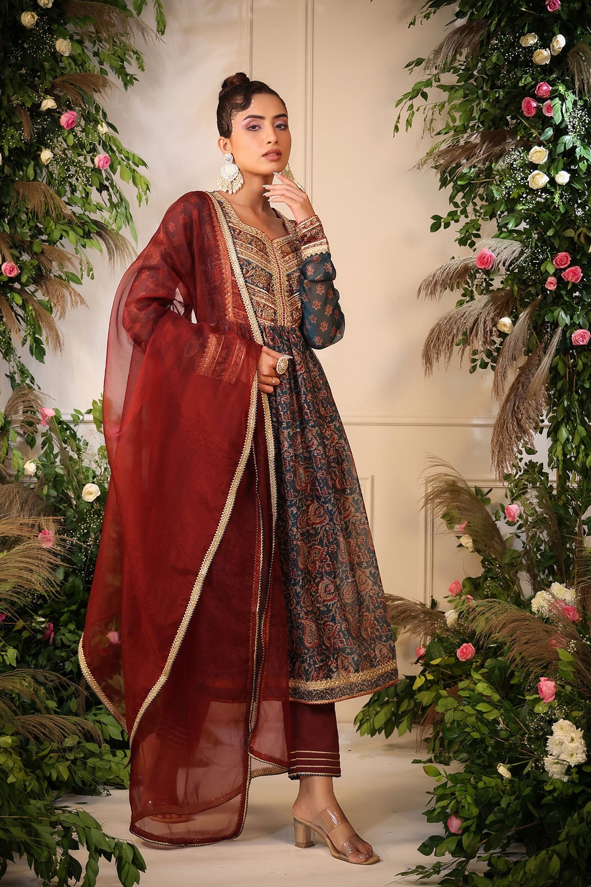Woman in traditional outfit with floral decorations and greenery
