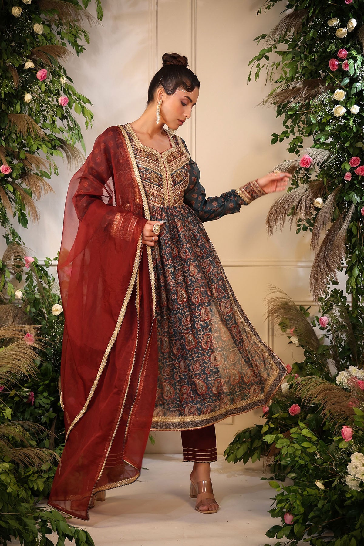 Woman in traditional outfit with floral decorations and greenery