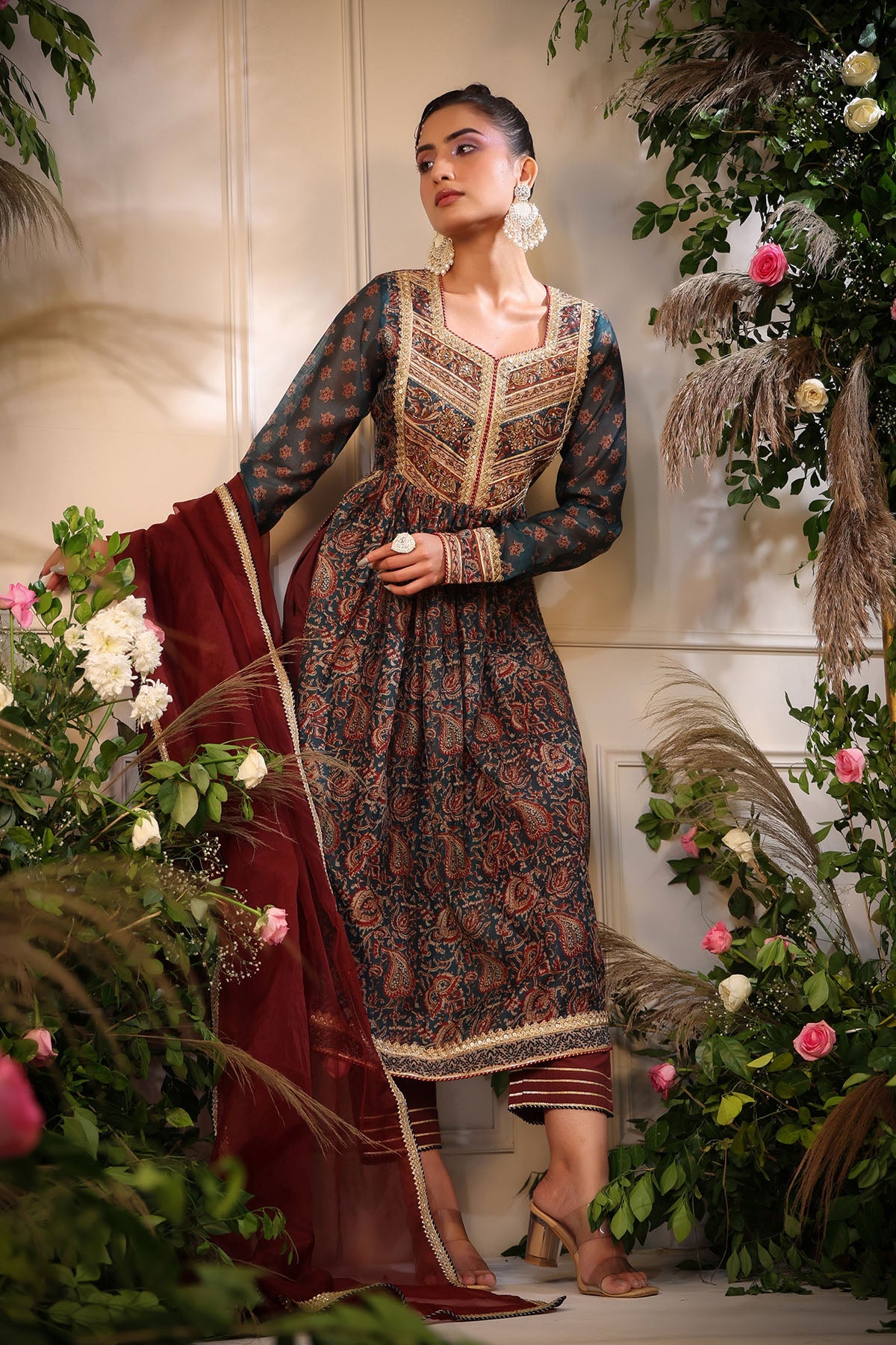 Woman in traditional outfit surrounded by floral decorations