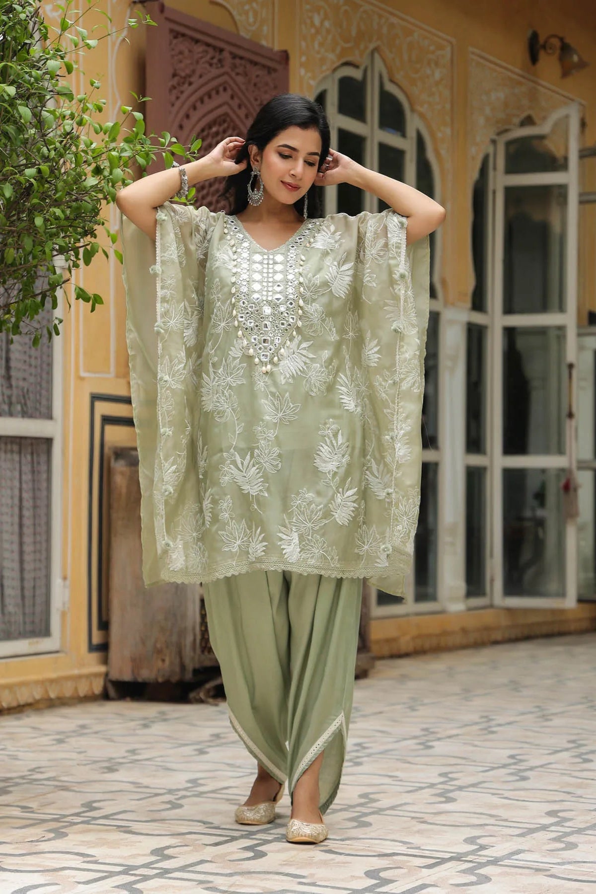 Woman in a traditional outfit standing in front of a decorative building.