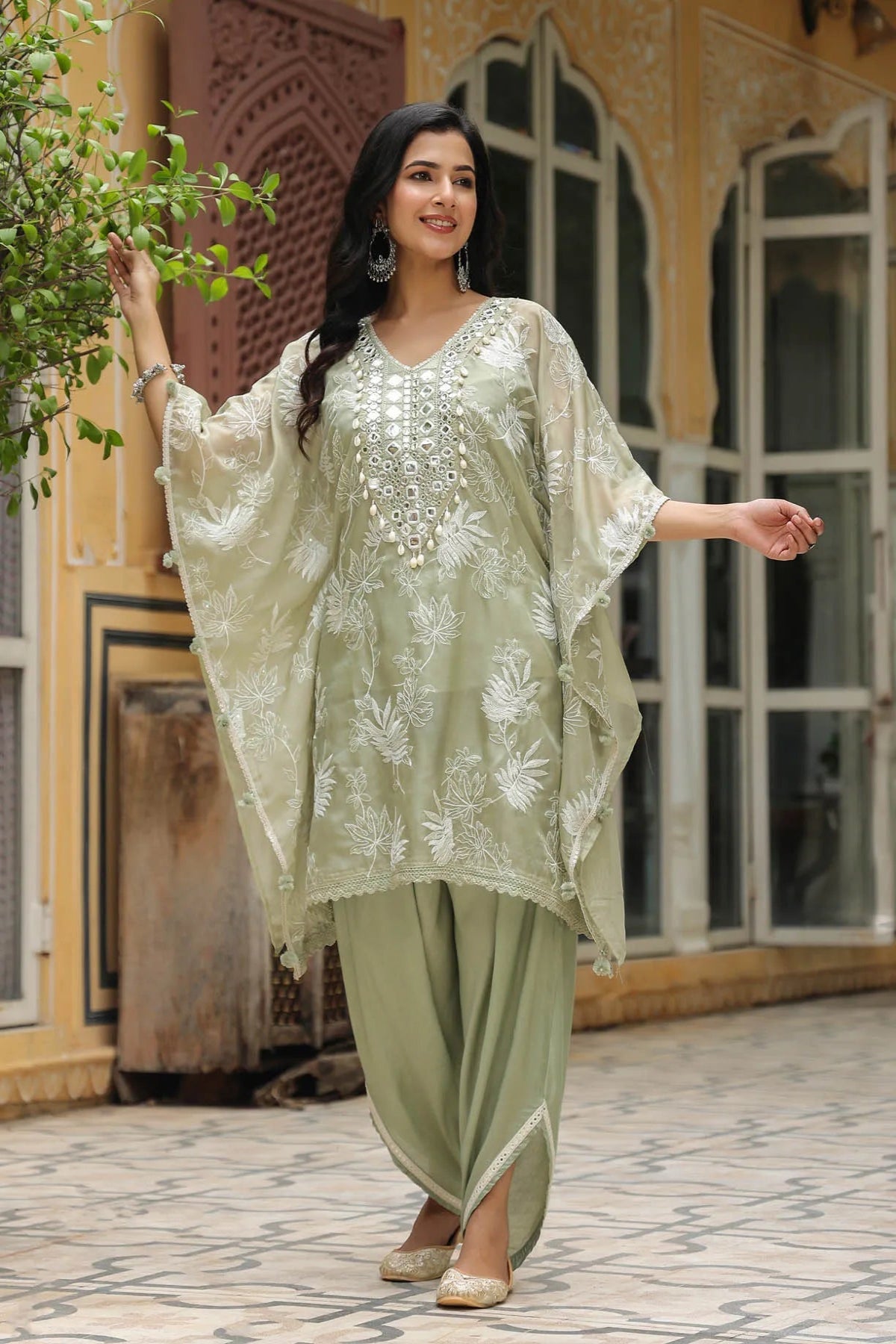 Woman in a traditional outfit standing in front of a decorative building.