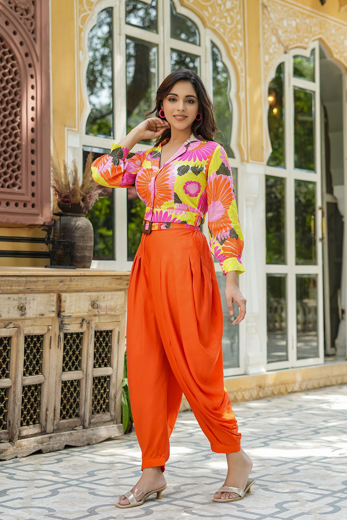 Woman in a colorful outfit standing in front of a decorative building entrance.