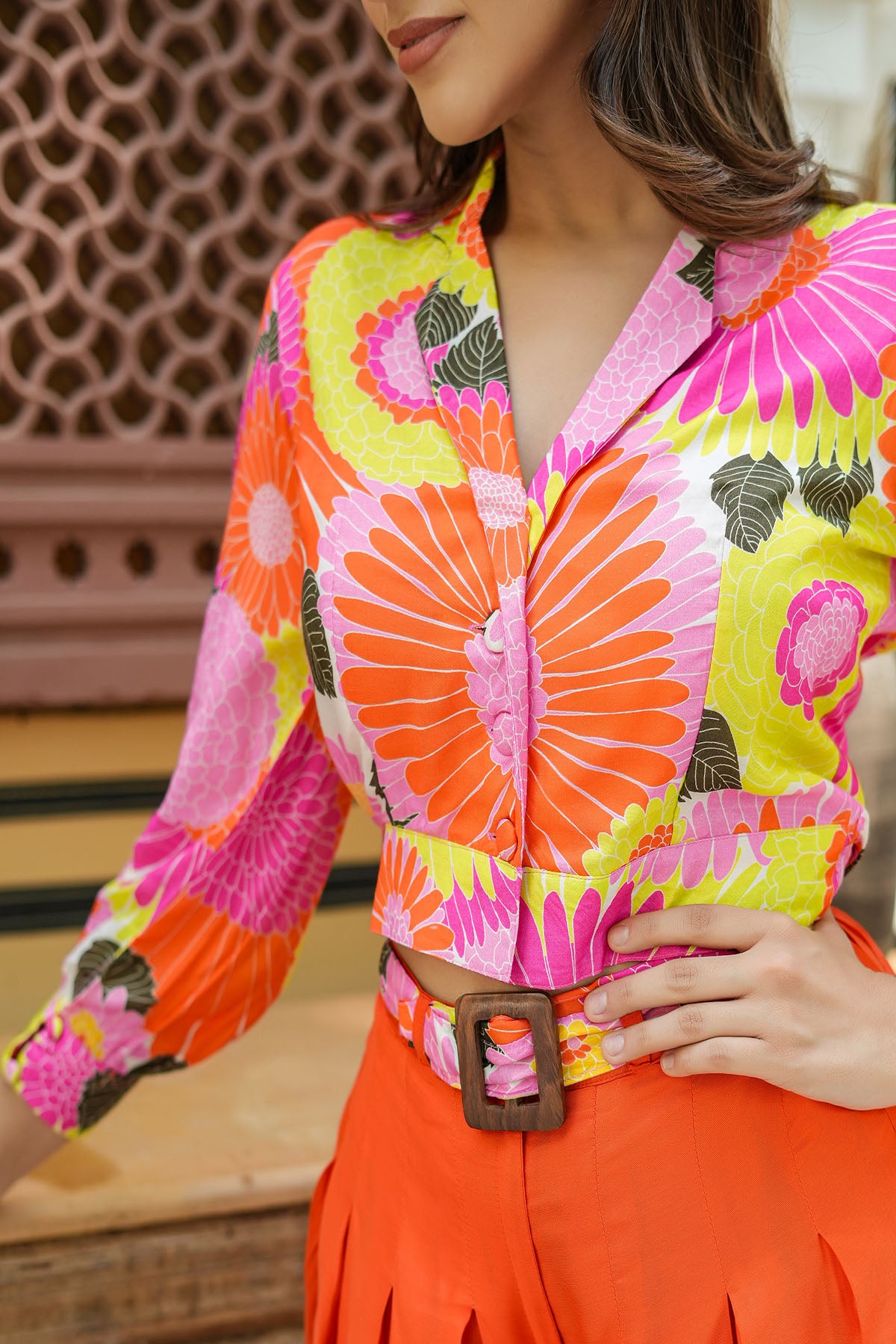 Person wearing a colorful patterned shirt with bright orange and pink design, standing against a blurred background.