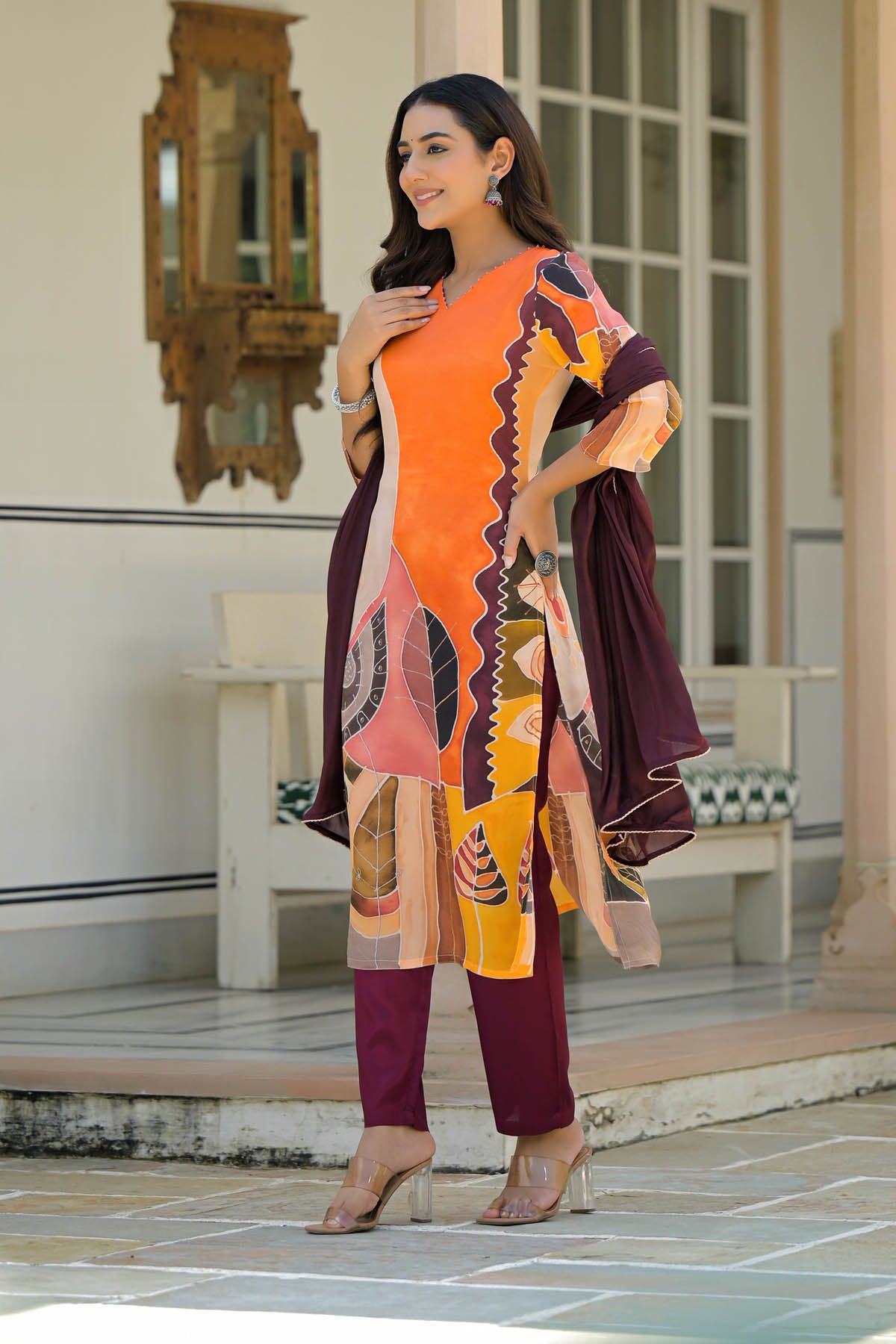 Woman in a colorful traditional outfit standing in an outdoor setting.