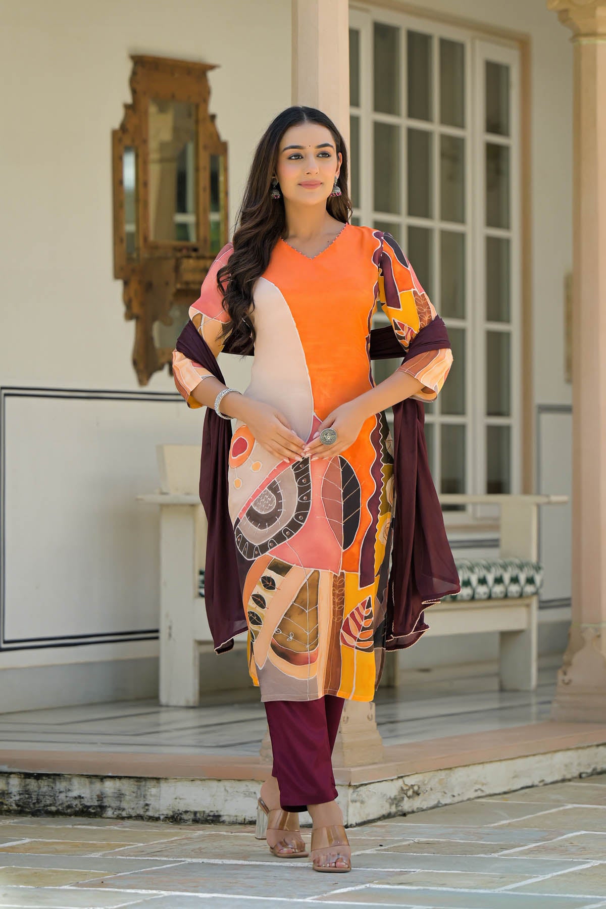 Woman wearing a colorful traditional outfit with a patterned shawl in an outdoor setting.