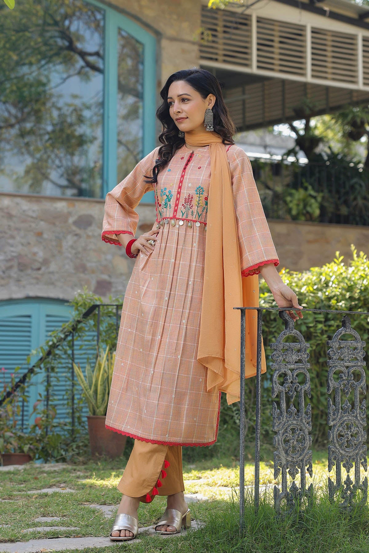 Woman in traditional outfit with floral design standing outdoors.