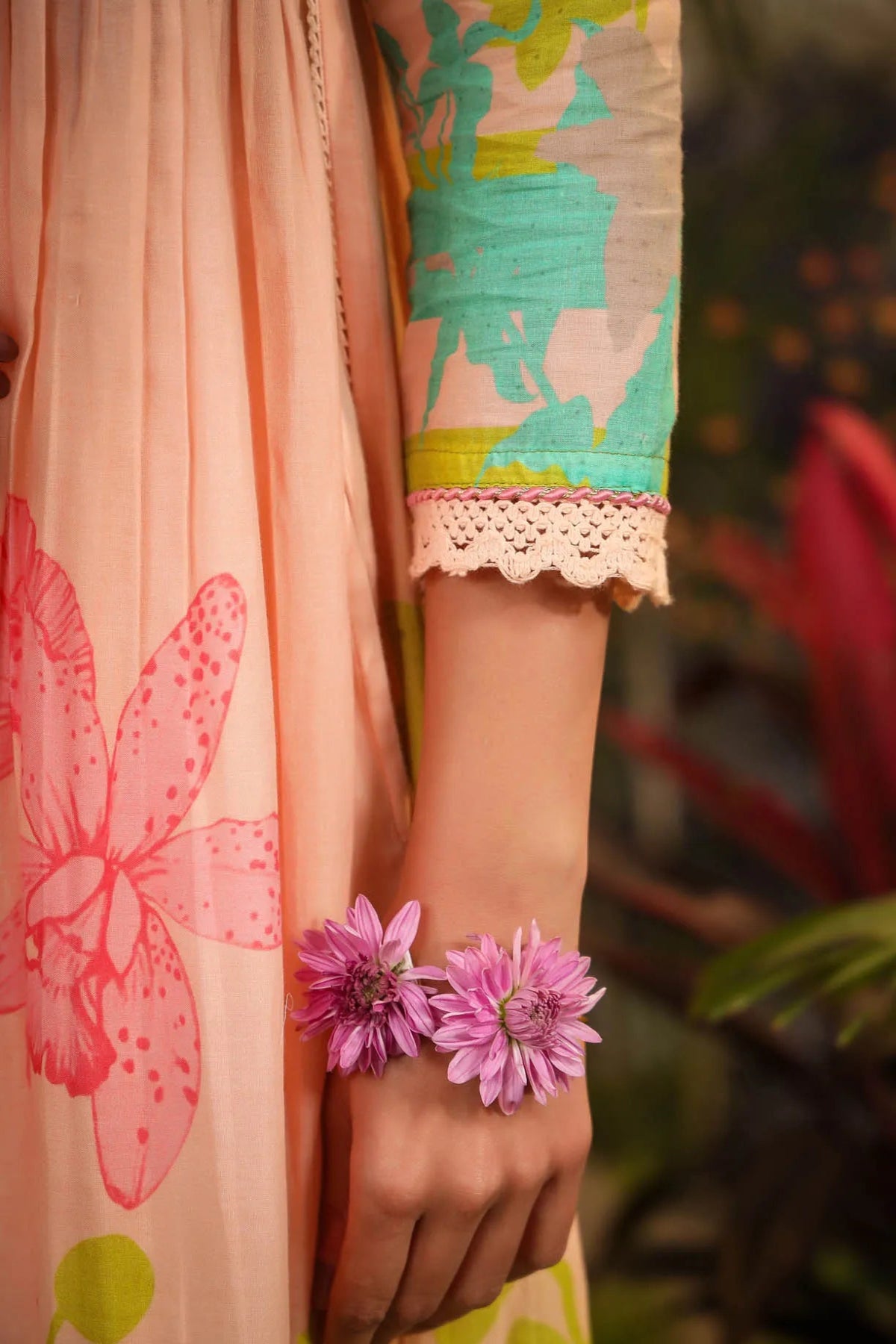 Person wearing a floral dress with pink flowers on a blurred natural background