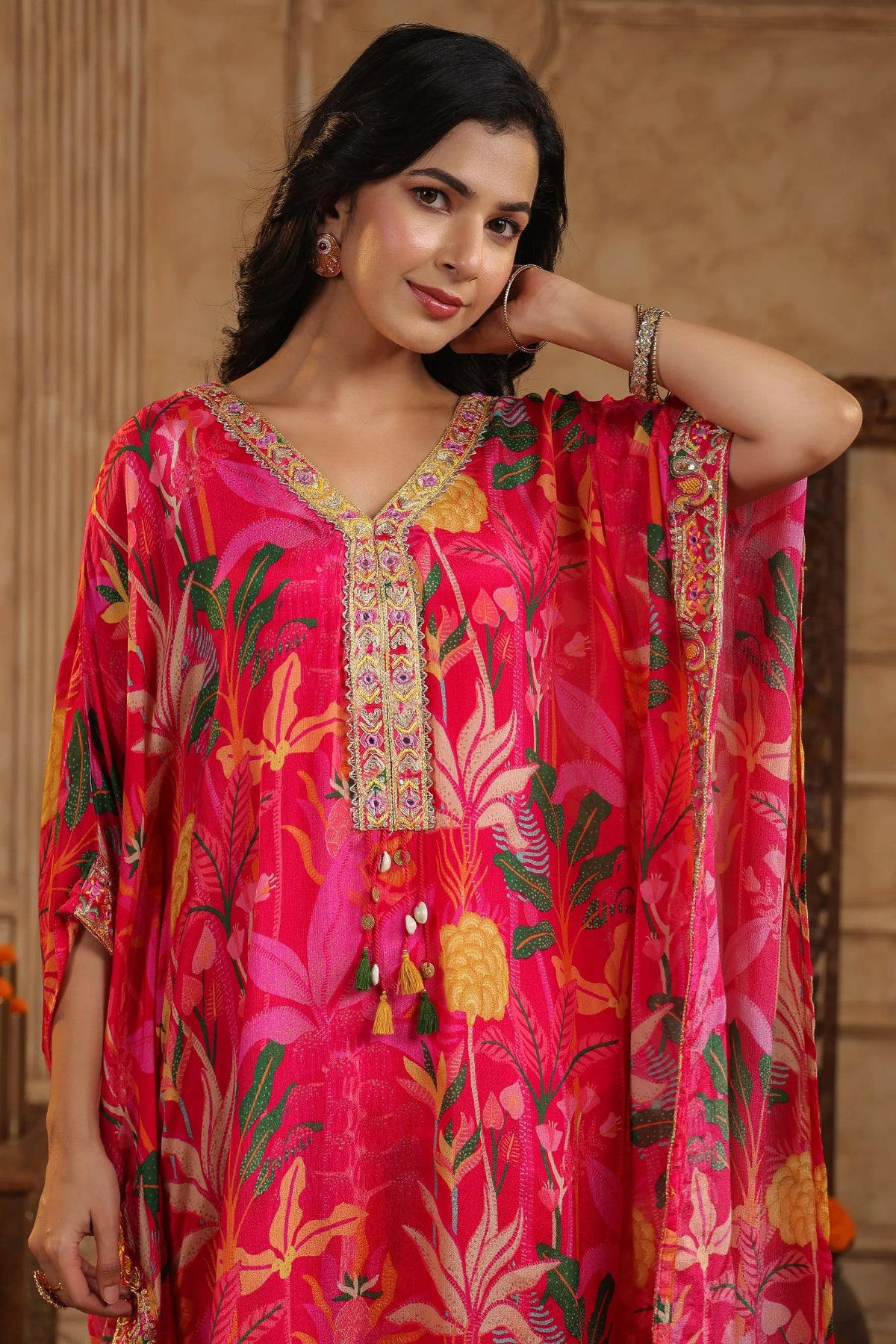 Woman wearing a vibrant pink floral dress with intricate patterns.