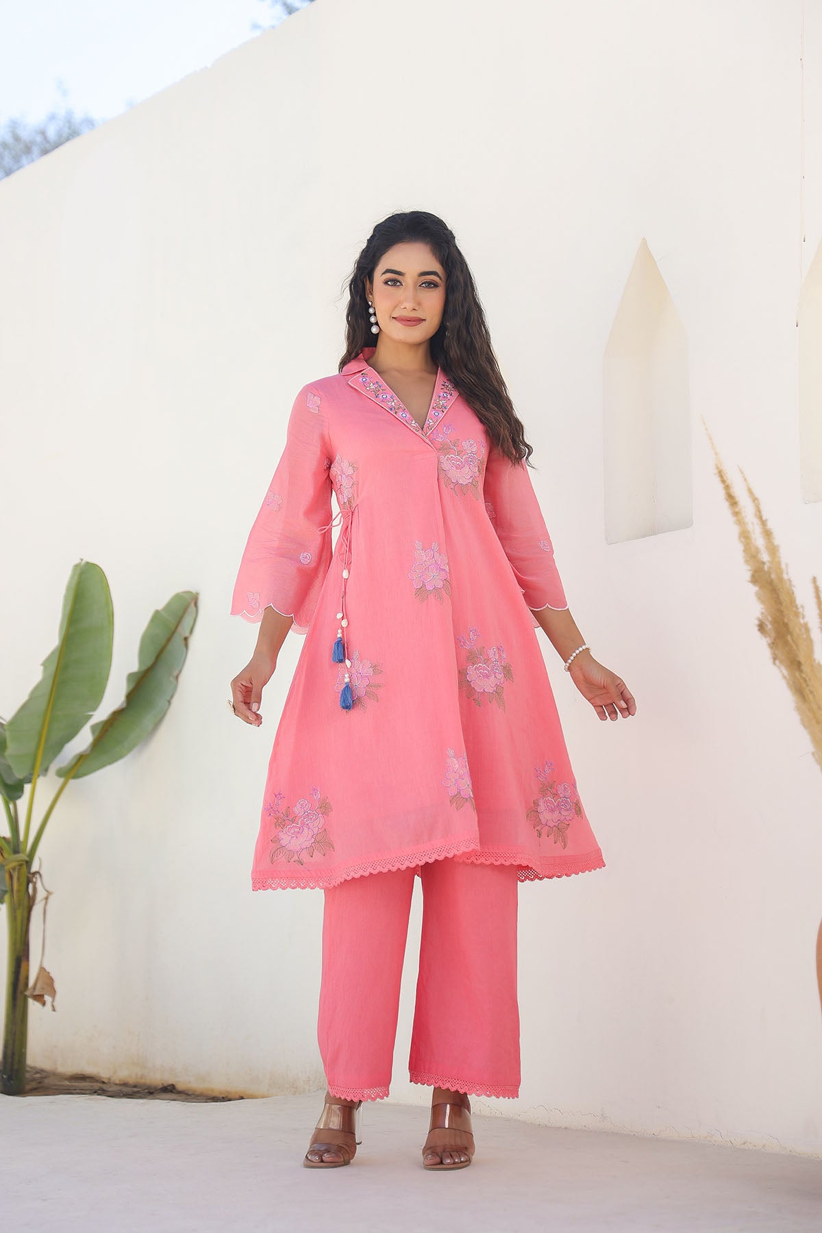 Woman wearing a pink traditional outfit with floral patterns against a white background