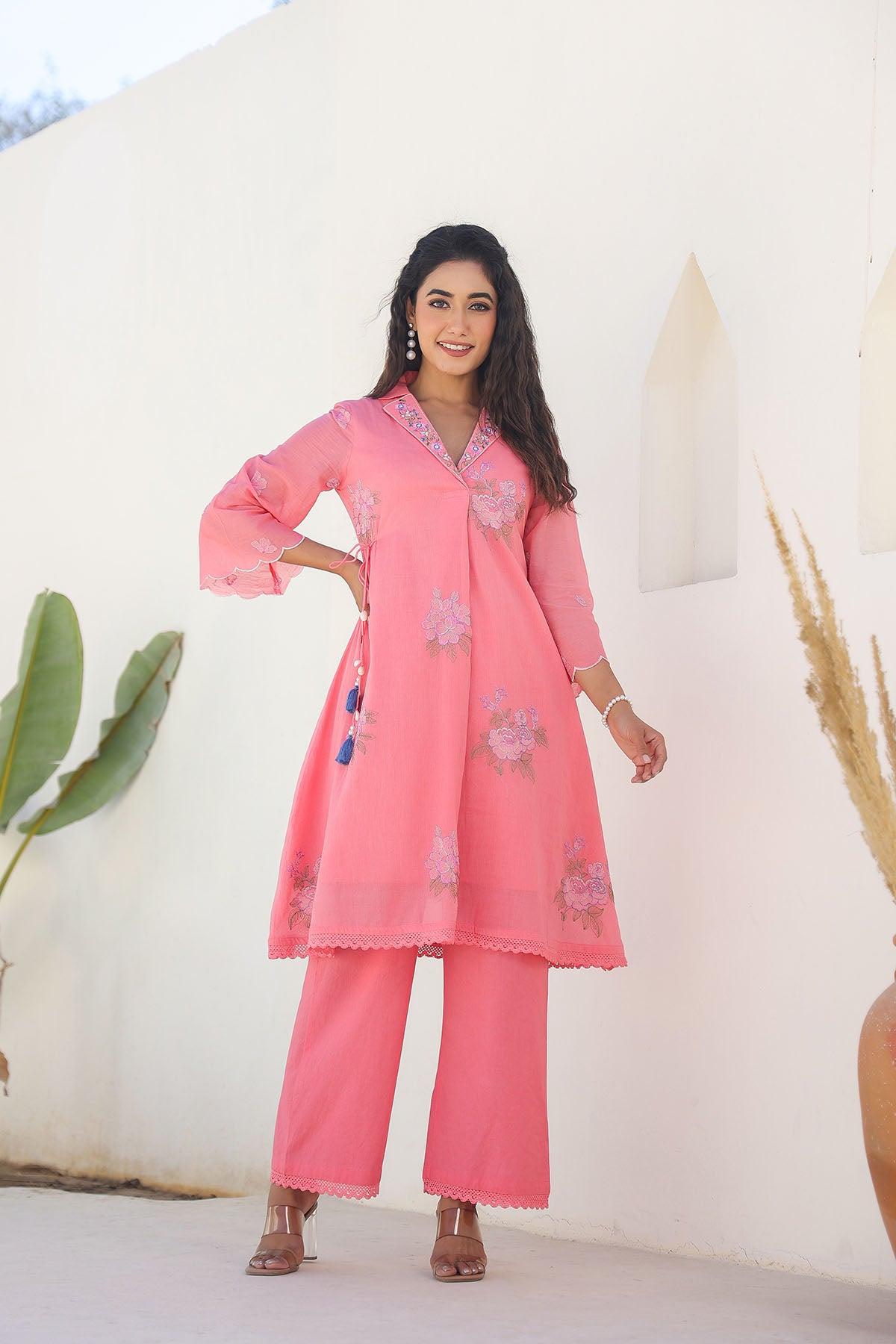 Woman wearing a pink traditional outfit with floral patterns against a white background