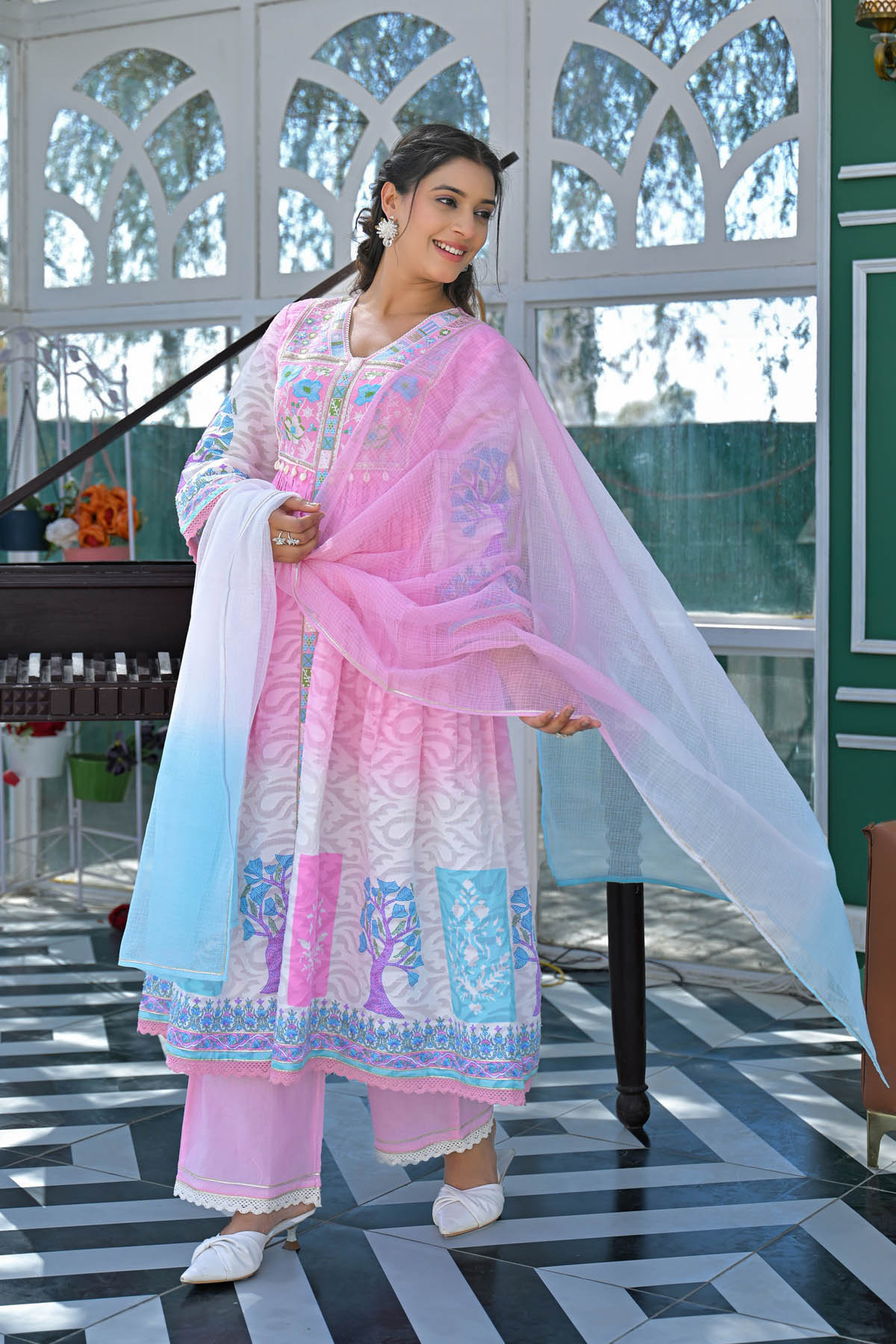 Woman in a traditional outfit with pink and white patterns standing indoors.