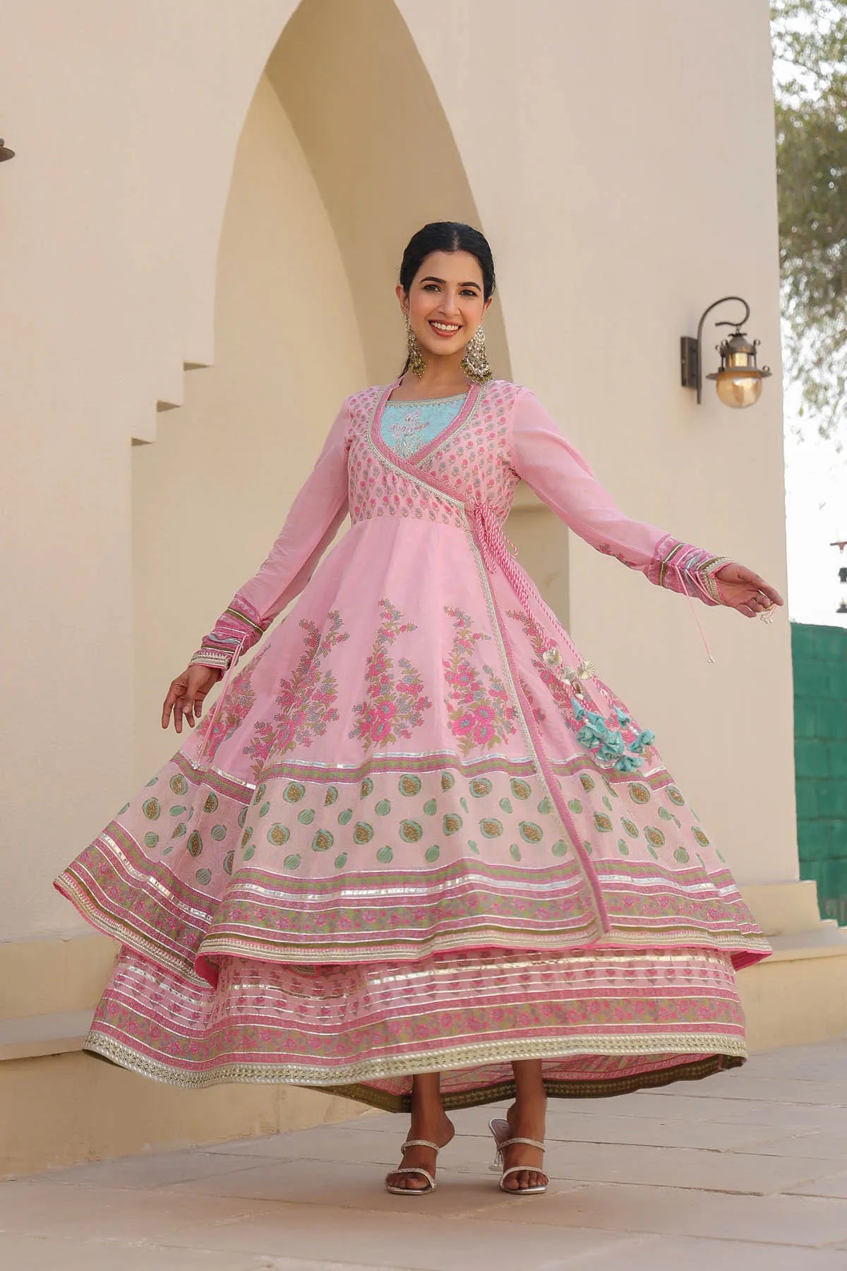 Woman in a pink traditional outfit standing in front of an archway.