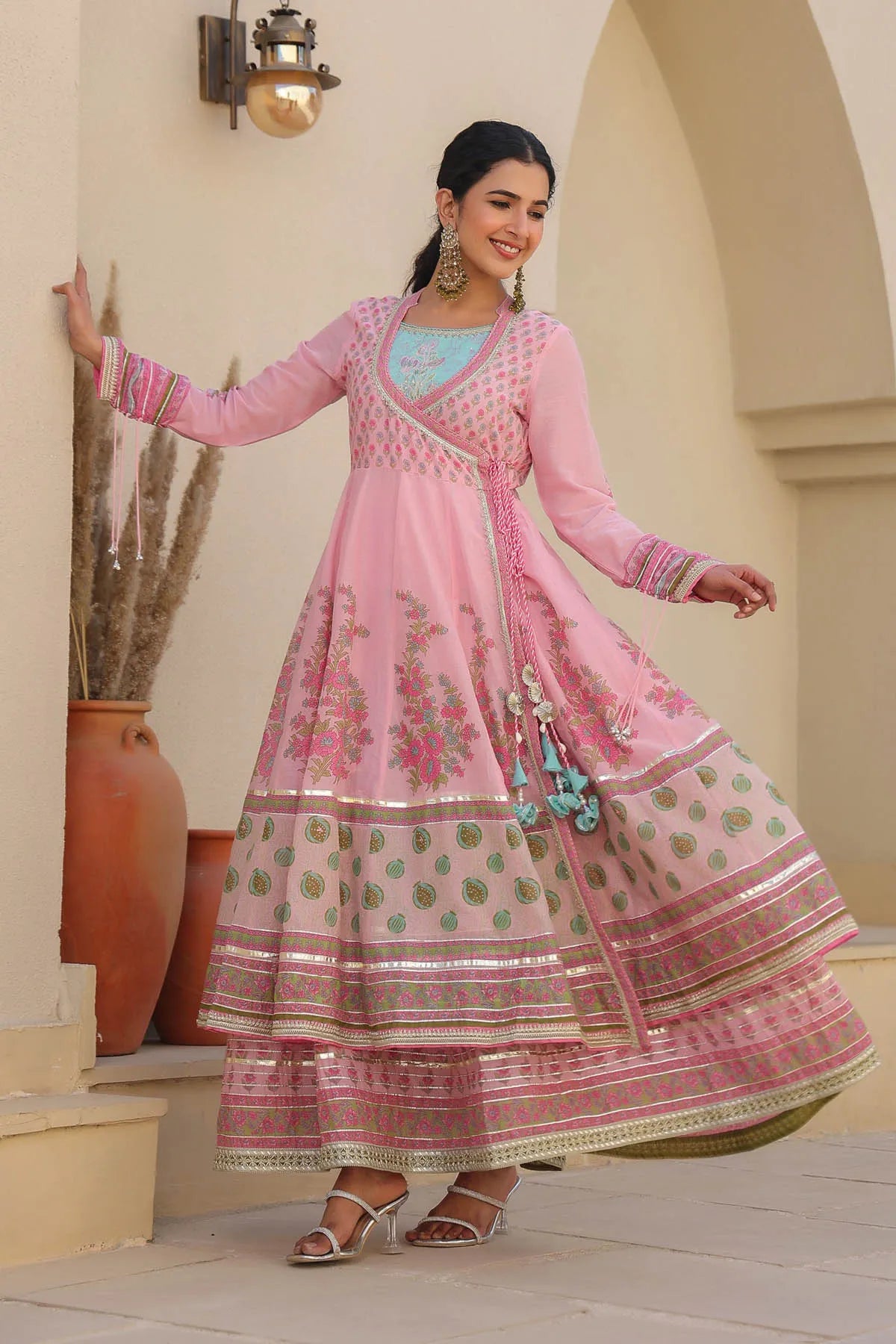 Woman in a pink traditional outfit standing in an outdoor setting.