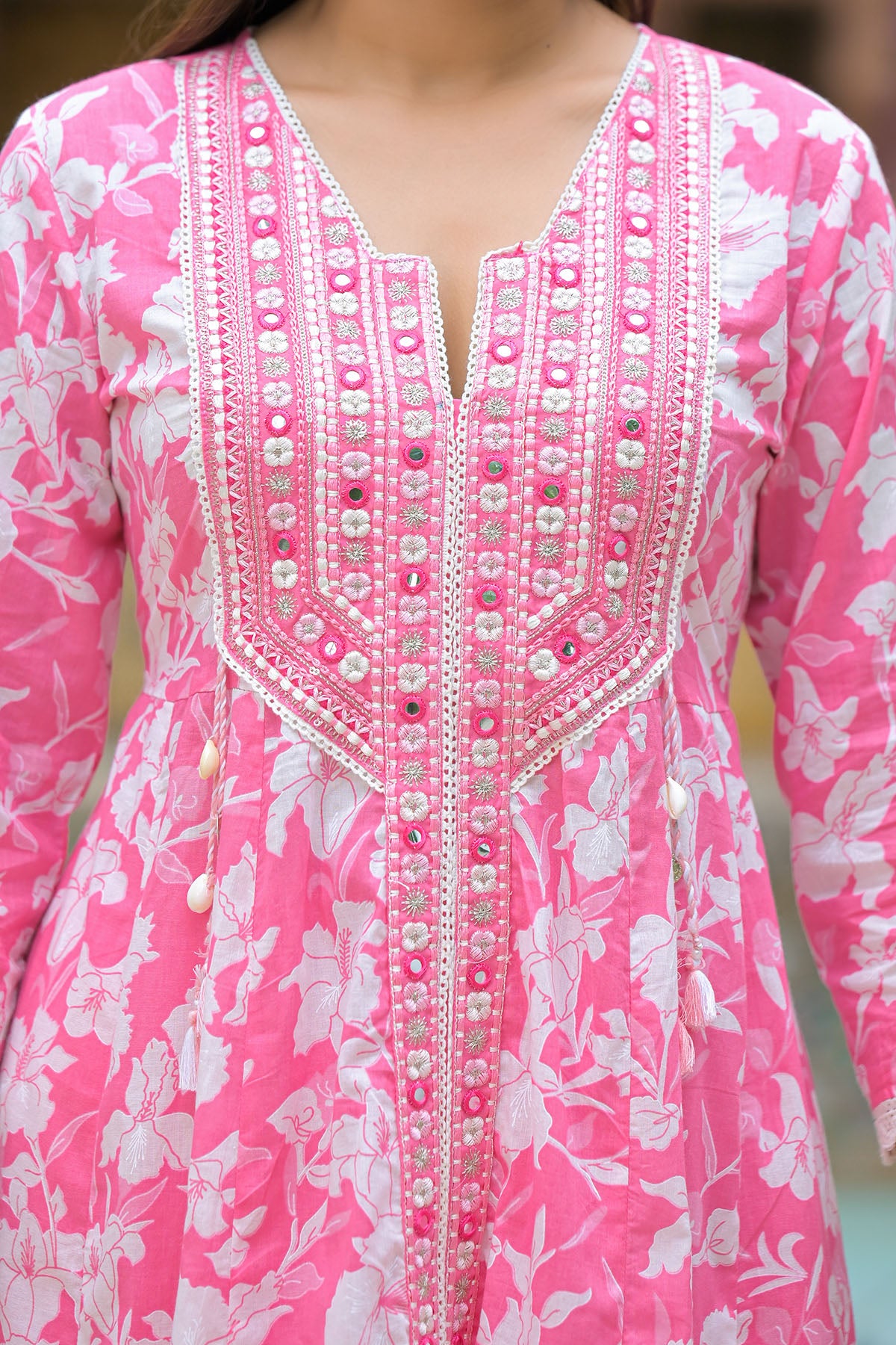 Close-up of a pink floral dress with intricate white embroidery.