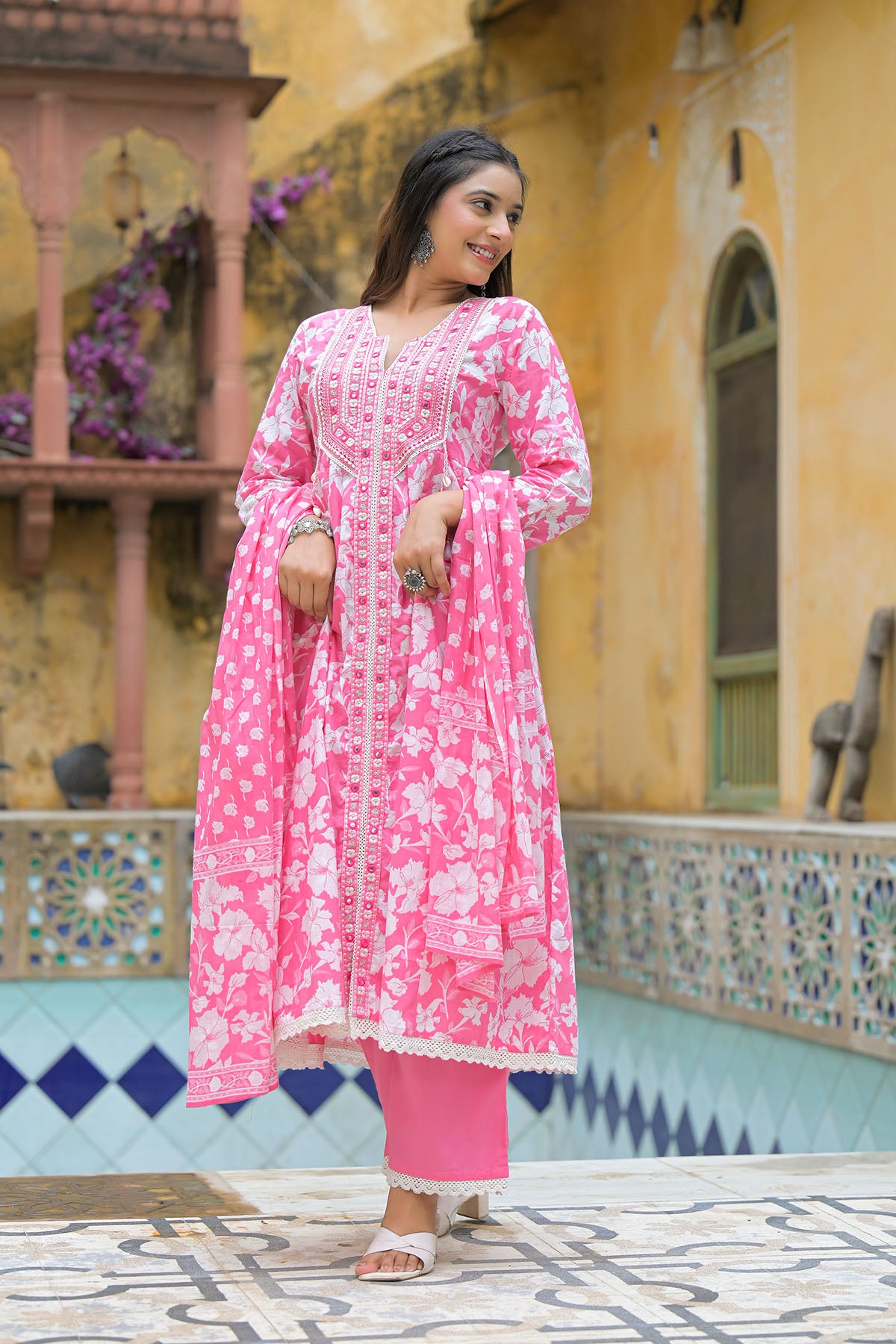 Woman wearing a pink floral outfit standing in front of a colorful architectural background