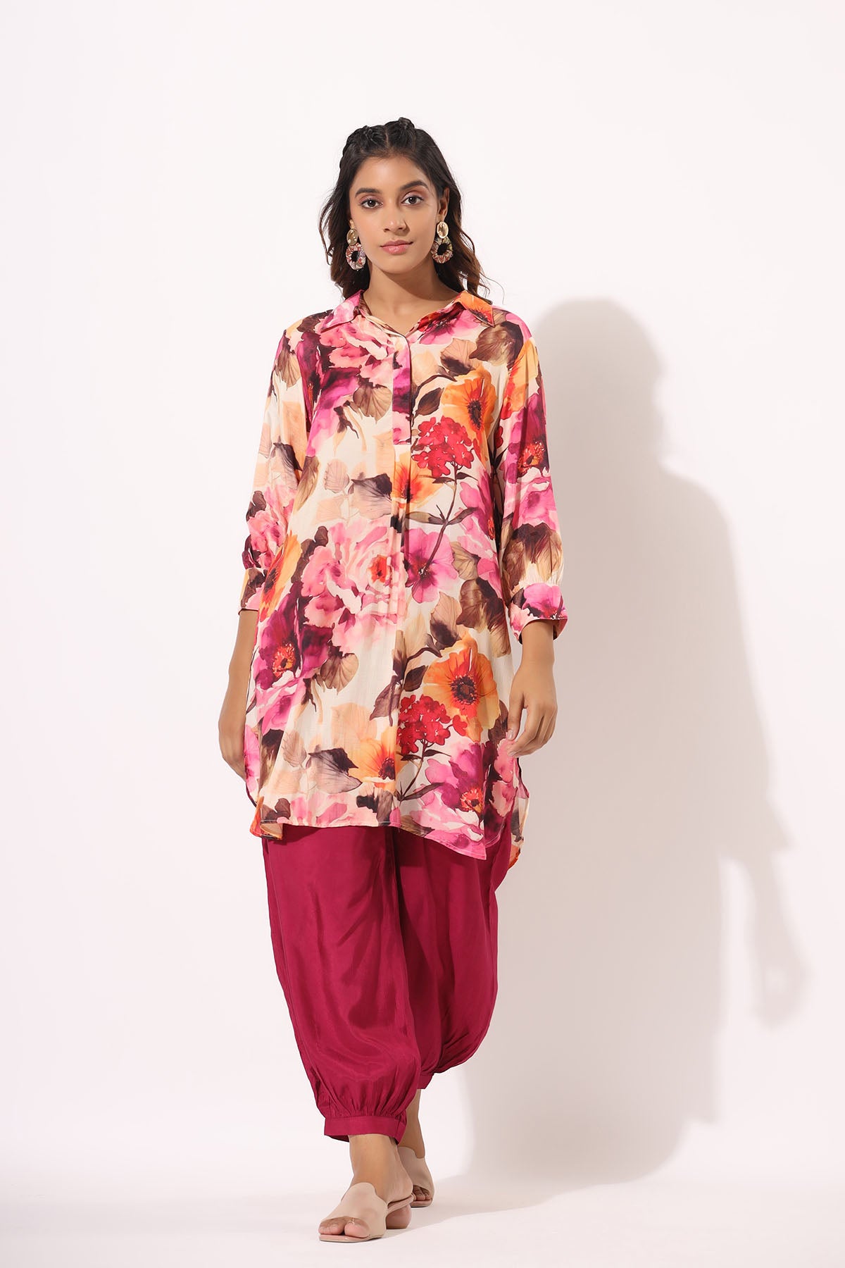 Woman wearing a floral top and pink pants on a white background