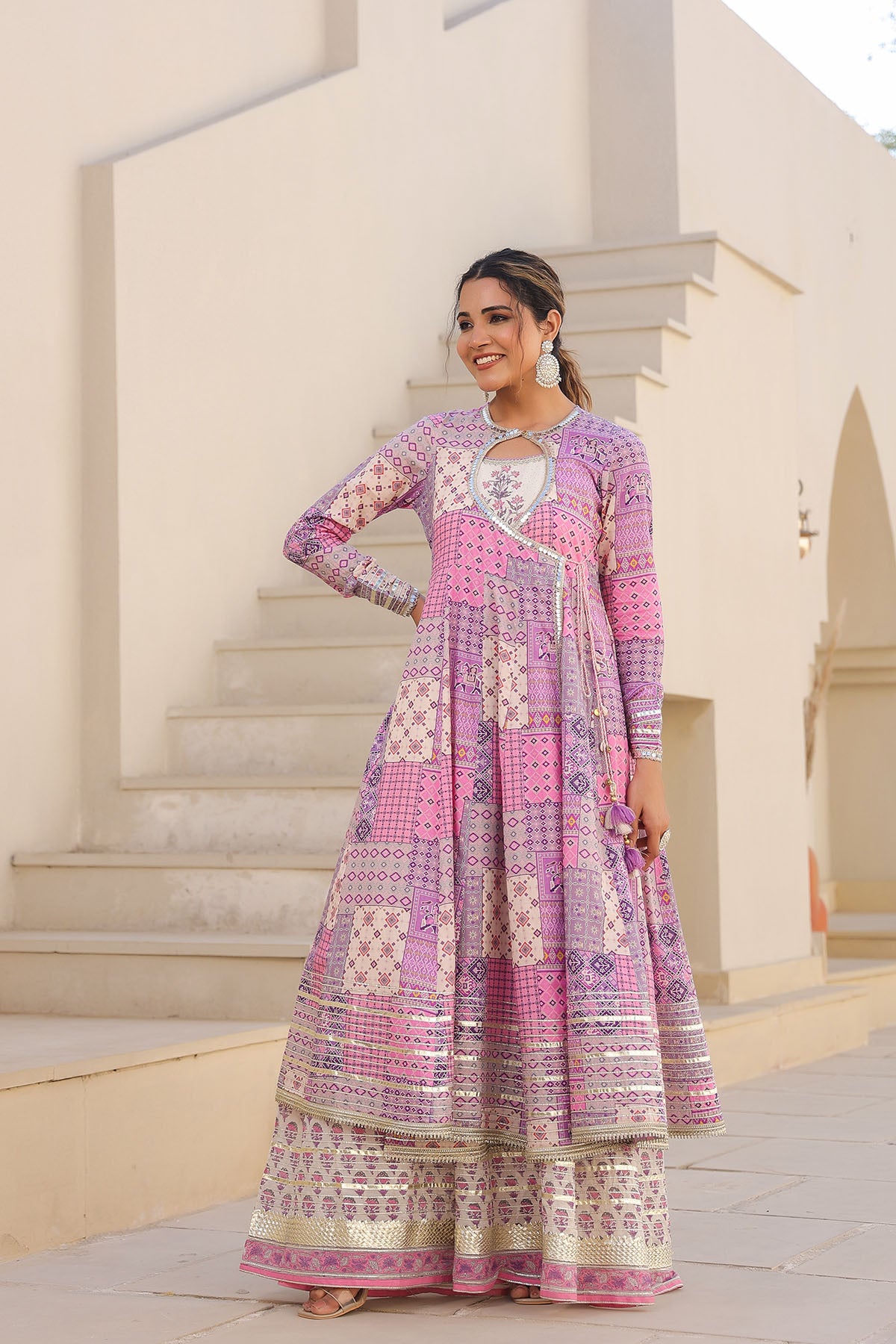 Woman in a colorful patterned dress standing outdoors with architectural background