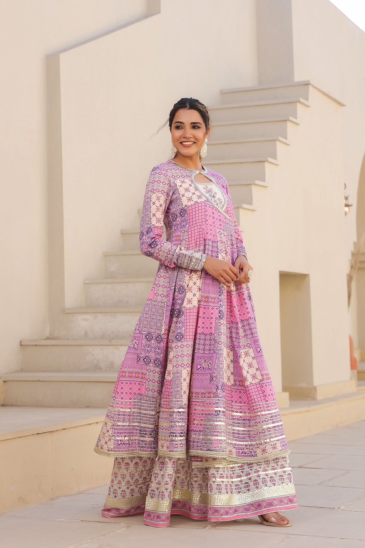 Woman wearing a patterned dress standing outdoors on steps.