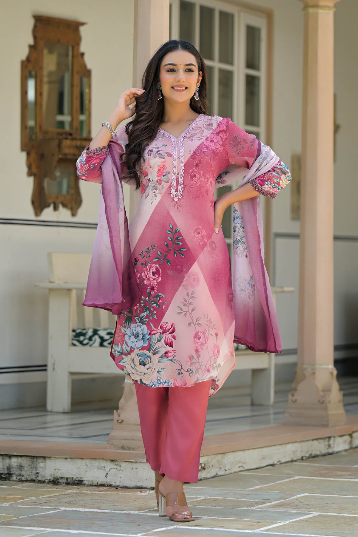 Woman wearing a pink floral outfit standing outdoors.