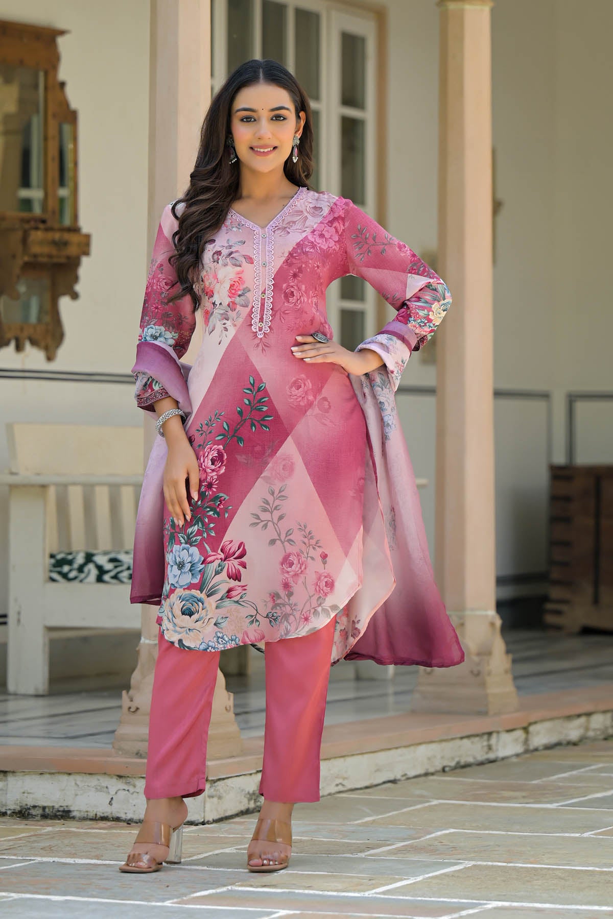 Woman wearing a pink embroidered outfit standing outdoors.