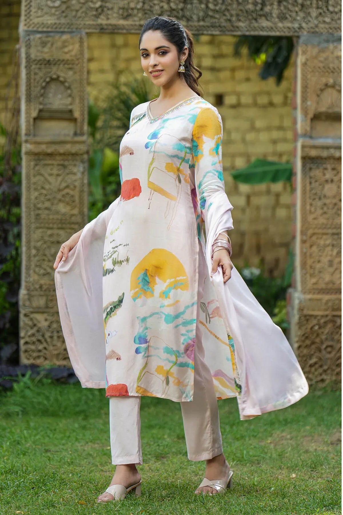 Woman in a colorful traditional outfit standing outdoors with decorative background