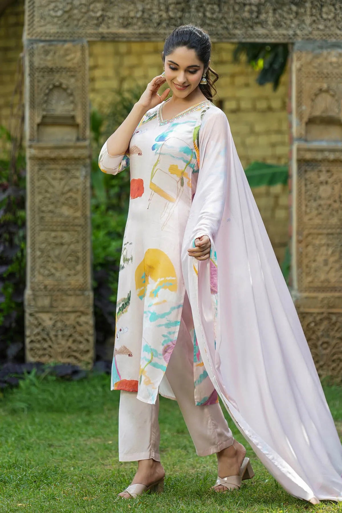 Woman in a colorful outfit standing outdoors with a decorative background