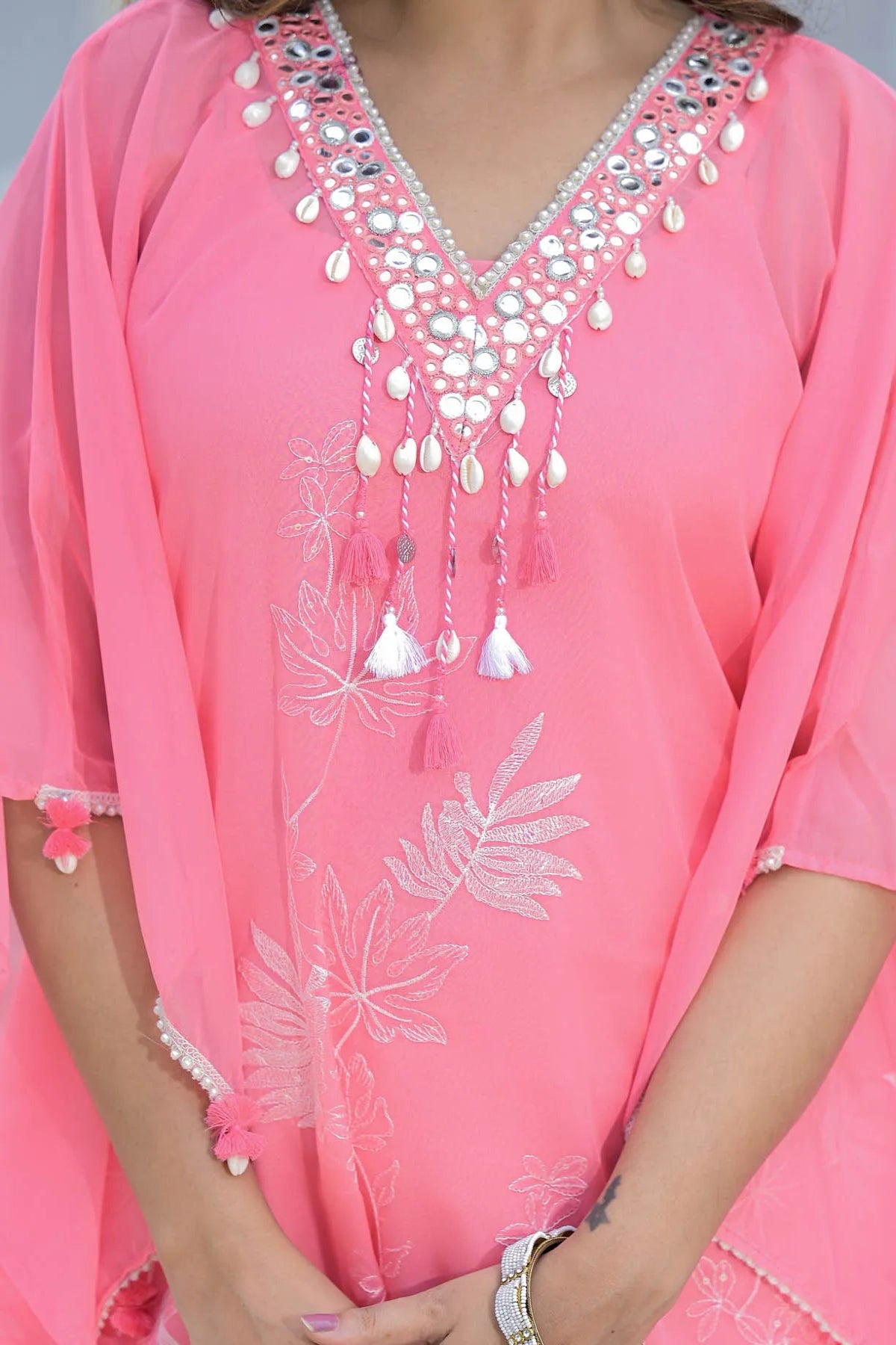 Pink dress with white floral embroidery and decorative neckline.