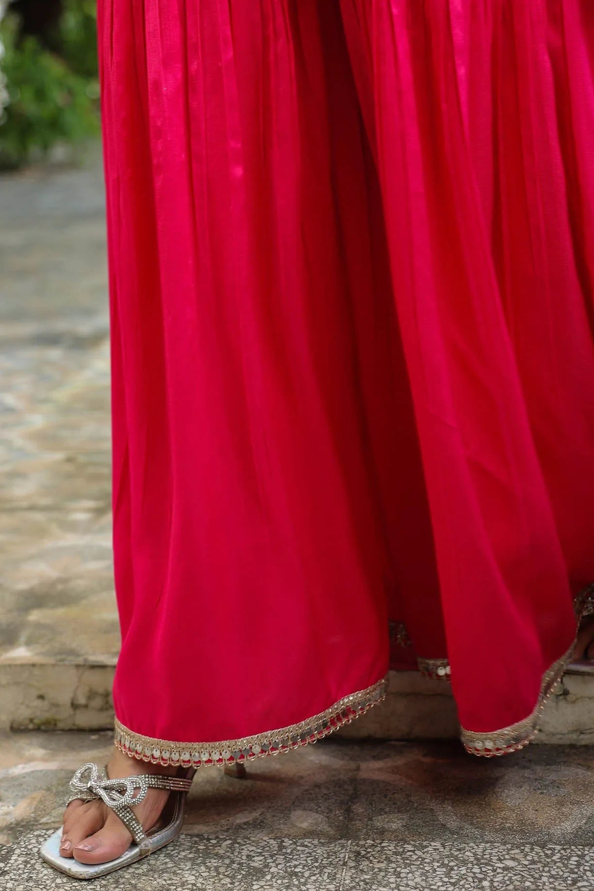 Close-up of a bright red skirt with a textured hem on a stone surface.