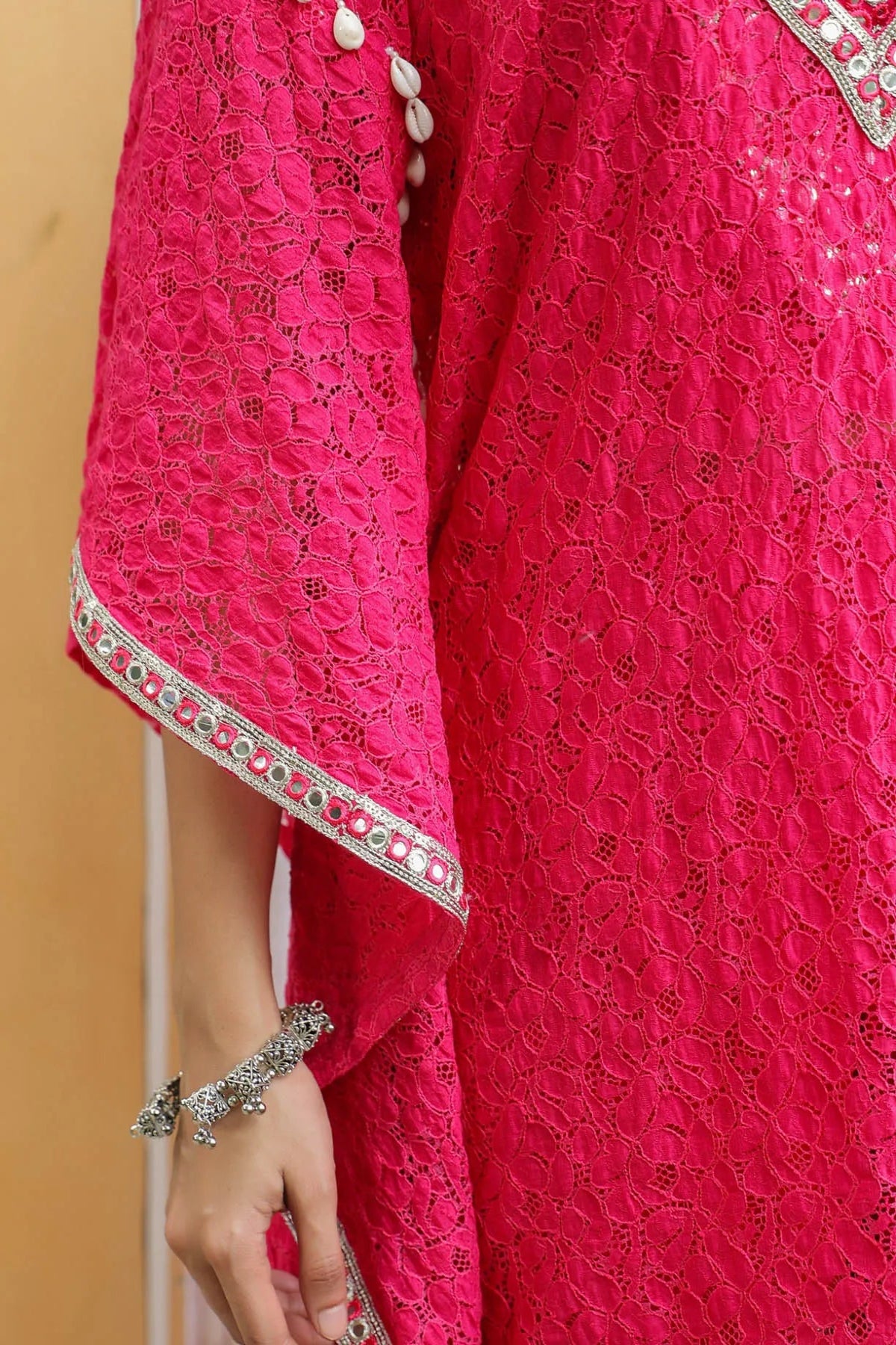 Close-up of a bright pink traditional outfit with intricate patterns and embellishments.