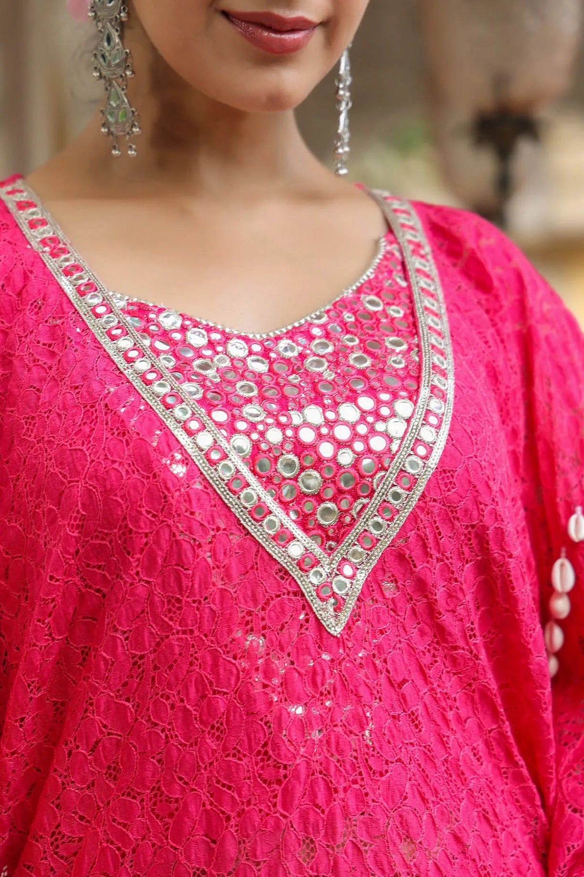 Close-up of a pink traditional outfit with silver mirror work on a blurred background