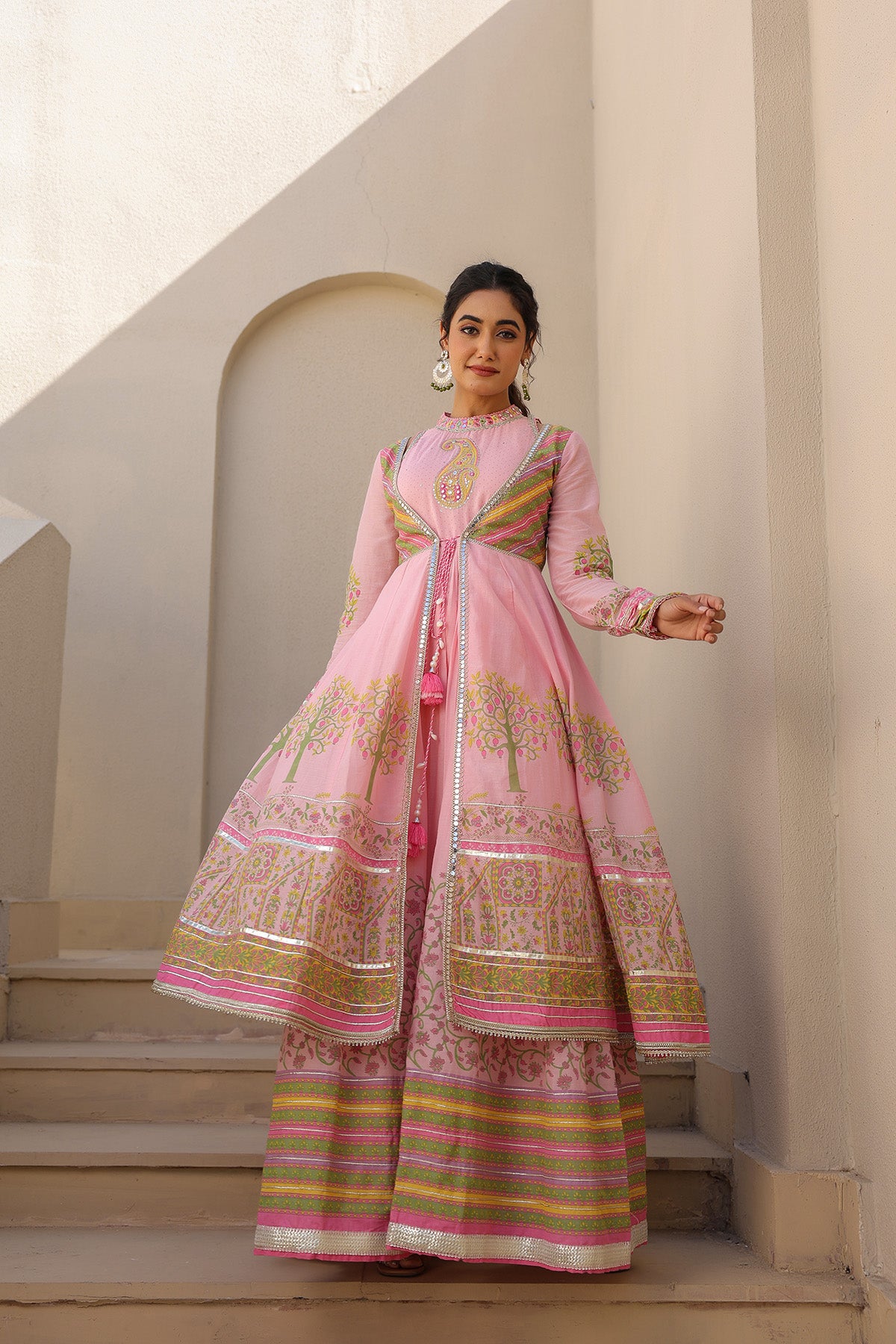 Woman in a pink traditional outfit standing in a sunlit architectural setting