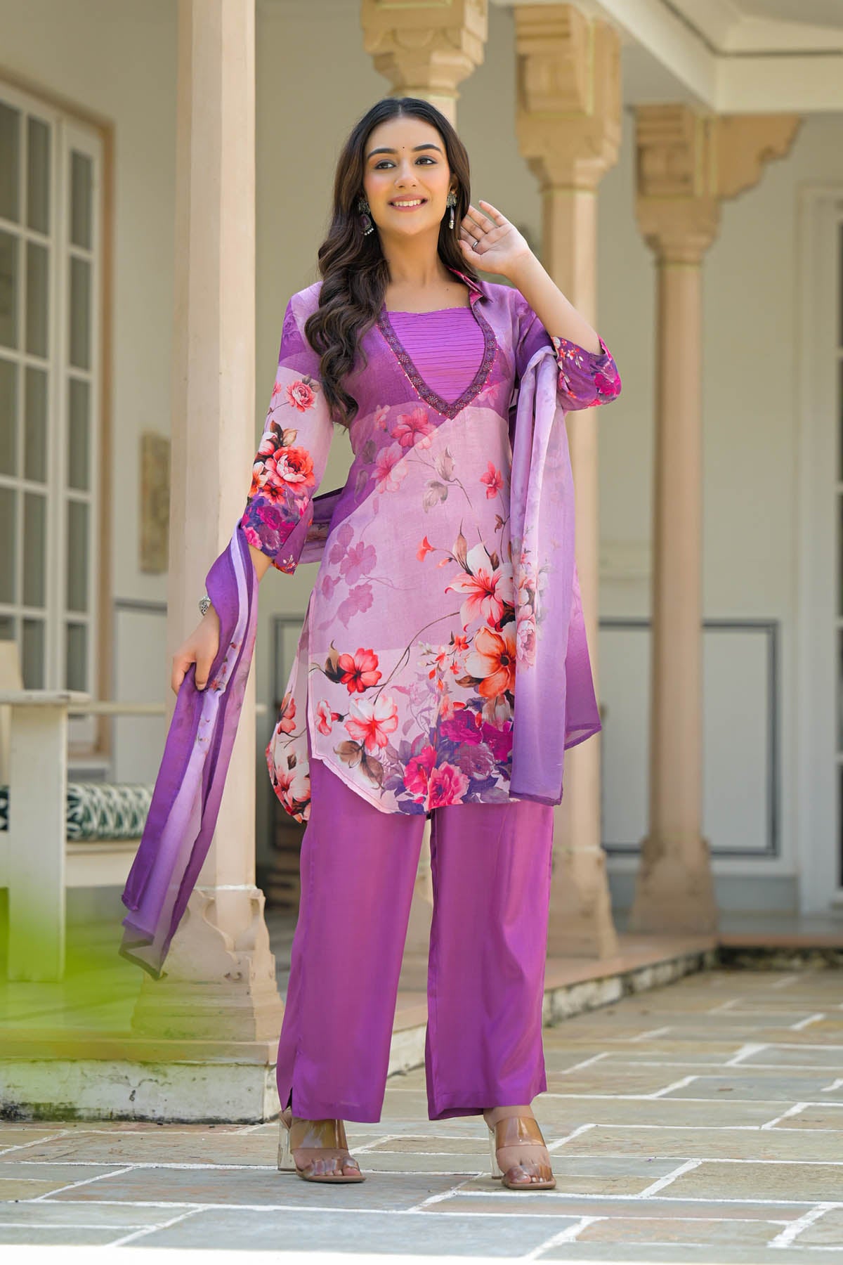 Woman in a purple floral outfit standing in front of architectural columns.