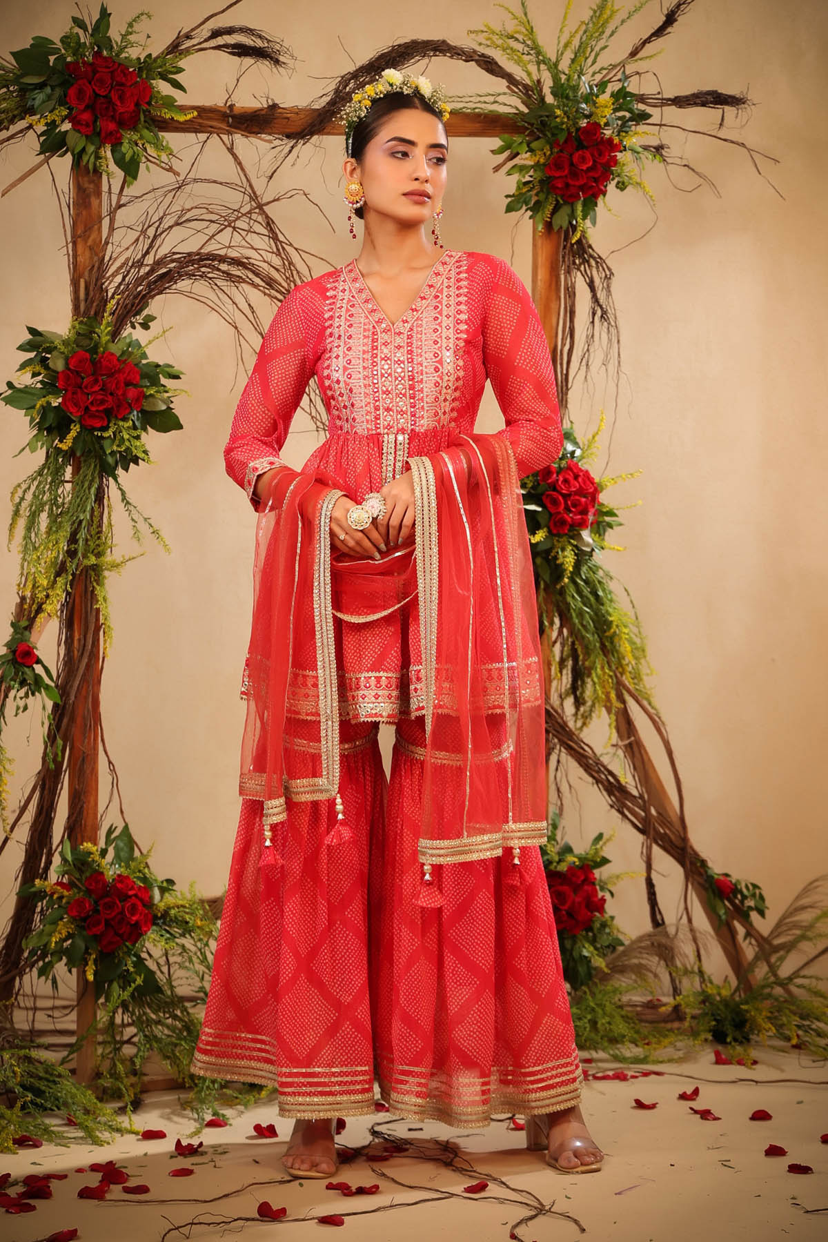 Woman in a traditional pink outfit with floral decorations in the background