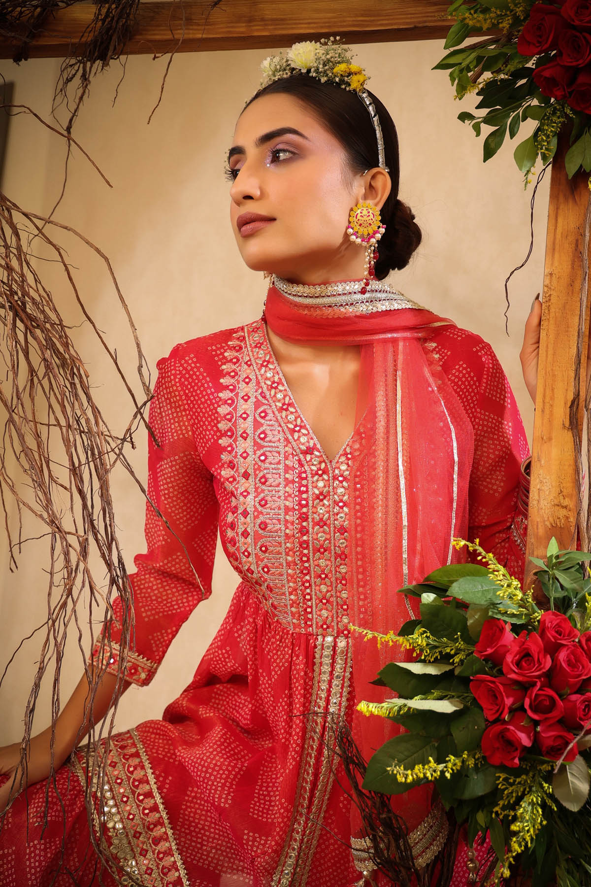 Woman in a red traditional outfit with floral decorations and jewelry.