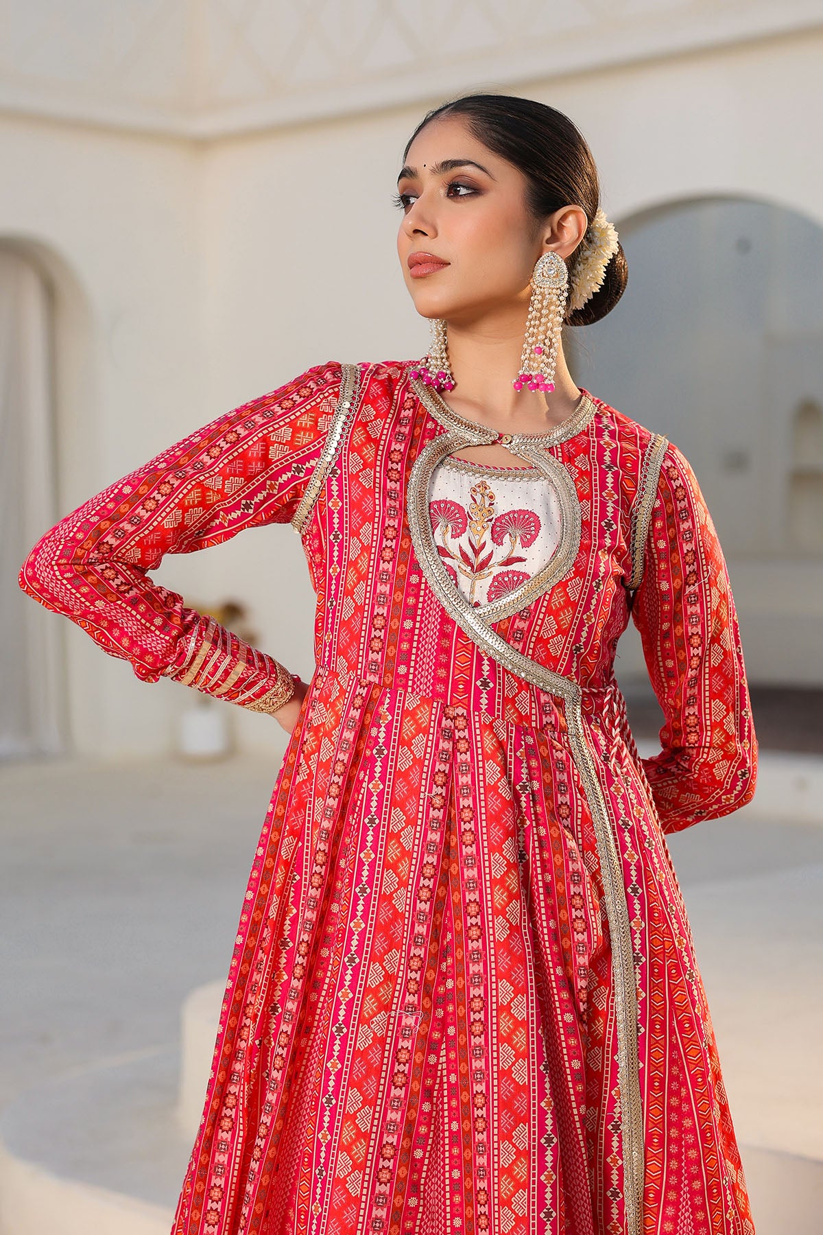 Woman wearing a red and gold traditional outfit with intricate patterns.