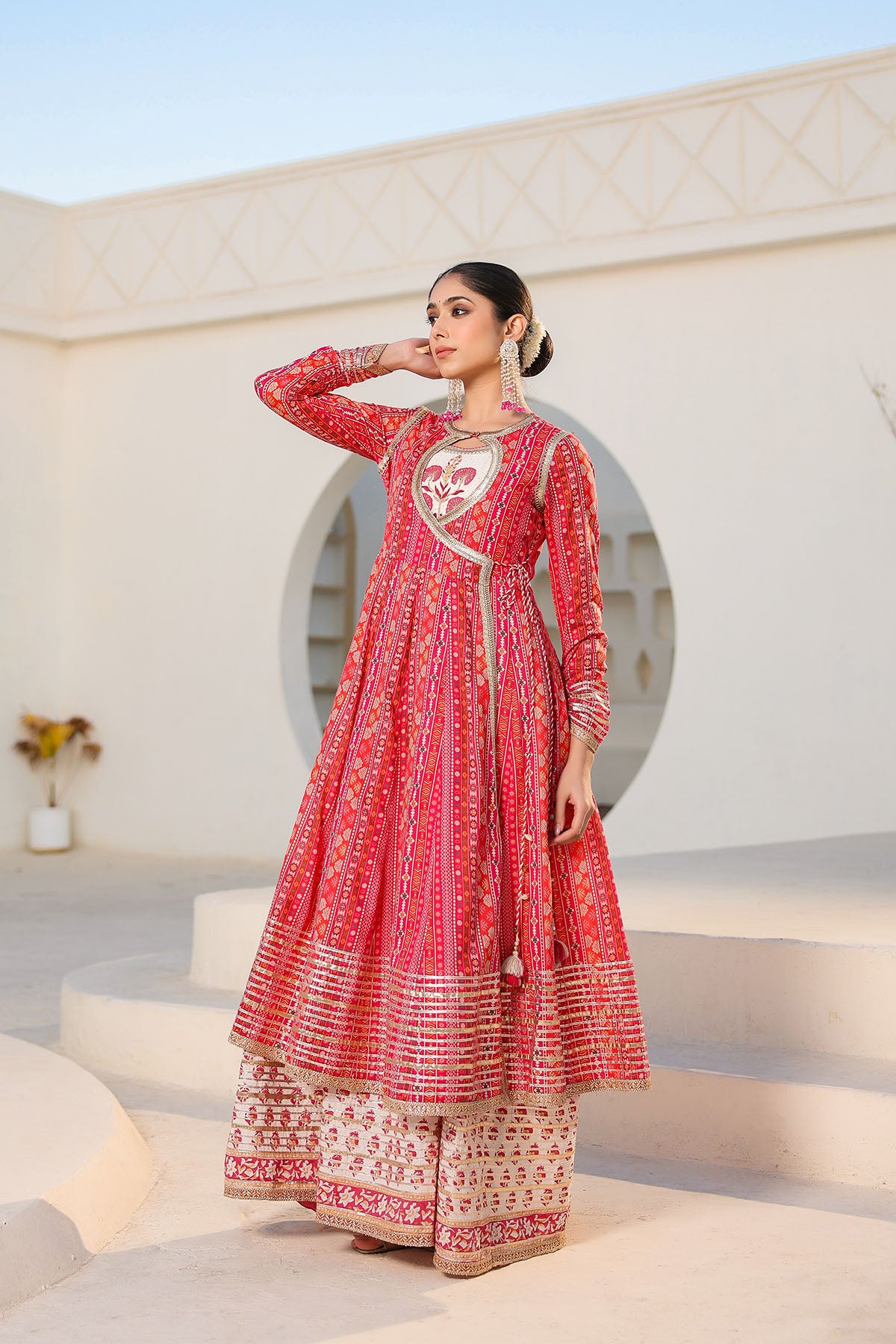 Woman in a red traditional outfit standing in front of a white archway.